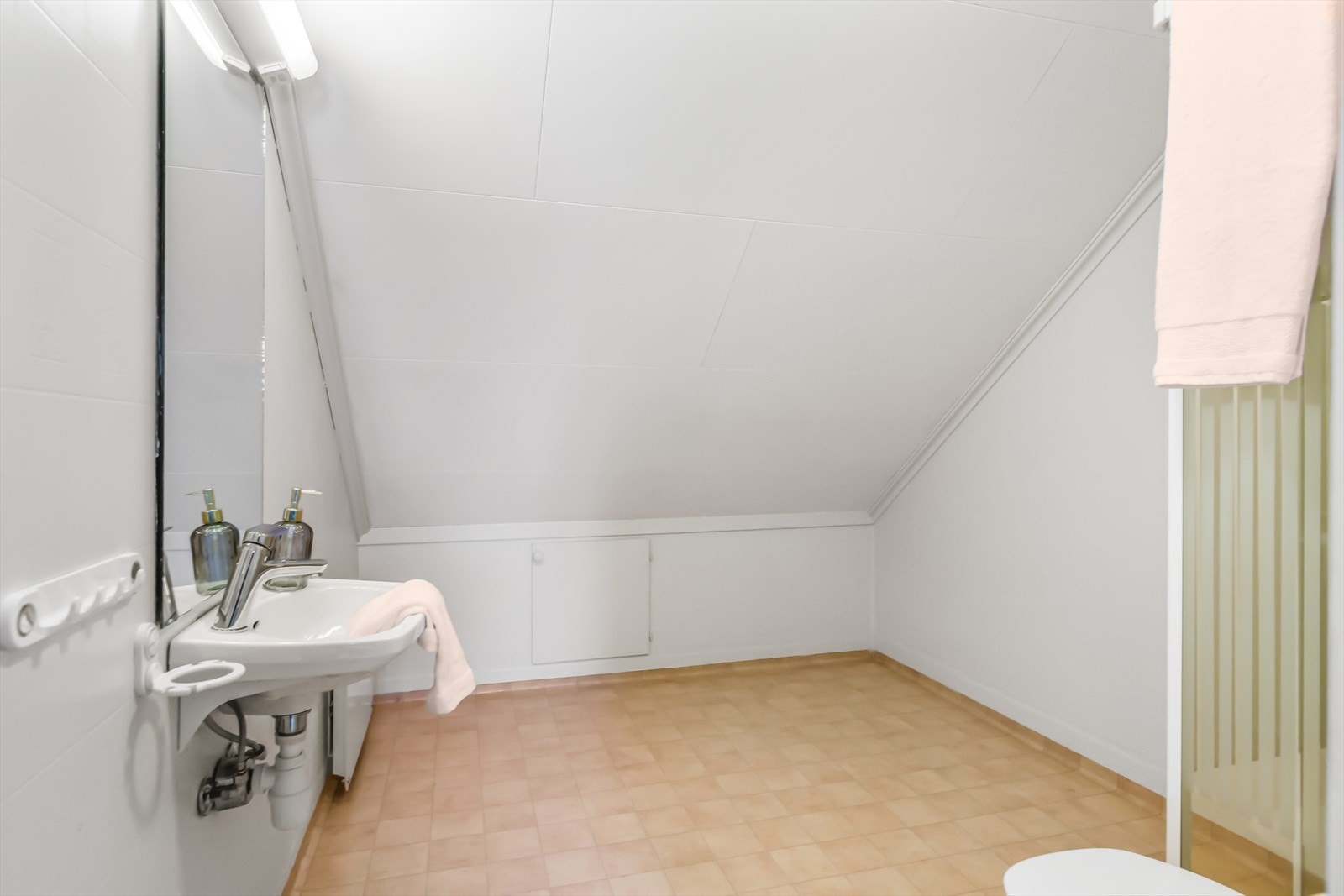 På badet er det toalett og et dusjhjørne med skyvedører. Det er montert en enkel servant og et speil med belysning. Galleribilde