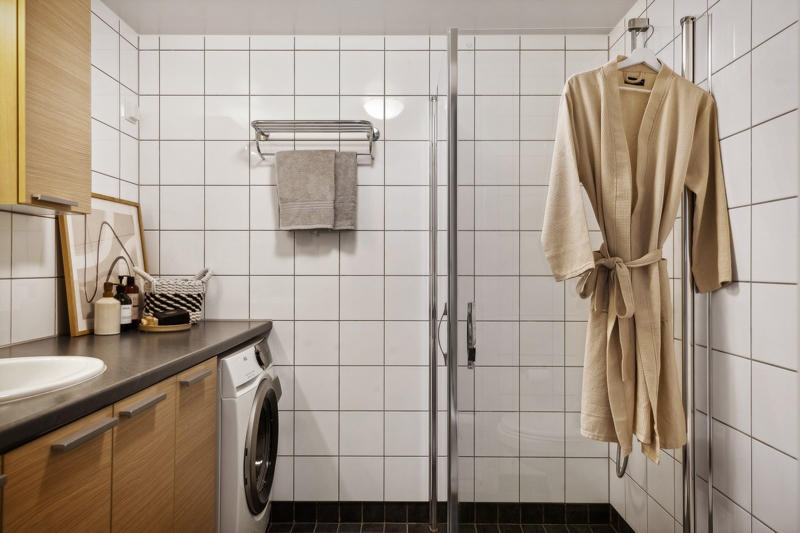 Det er etablert dusjvegger av glass, vegghengt toalett, innredning med servant, og opplegg for vaskemaskin på baderommet. Galleribilde