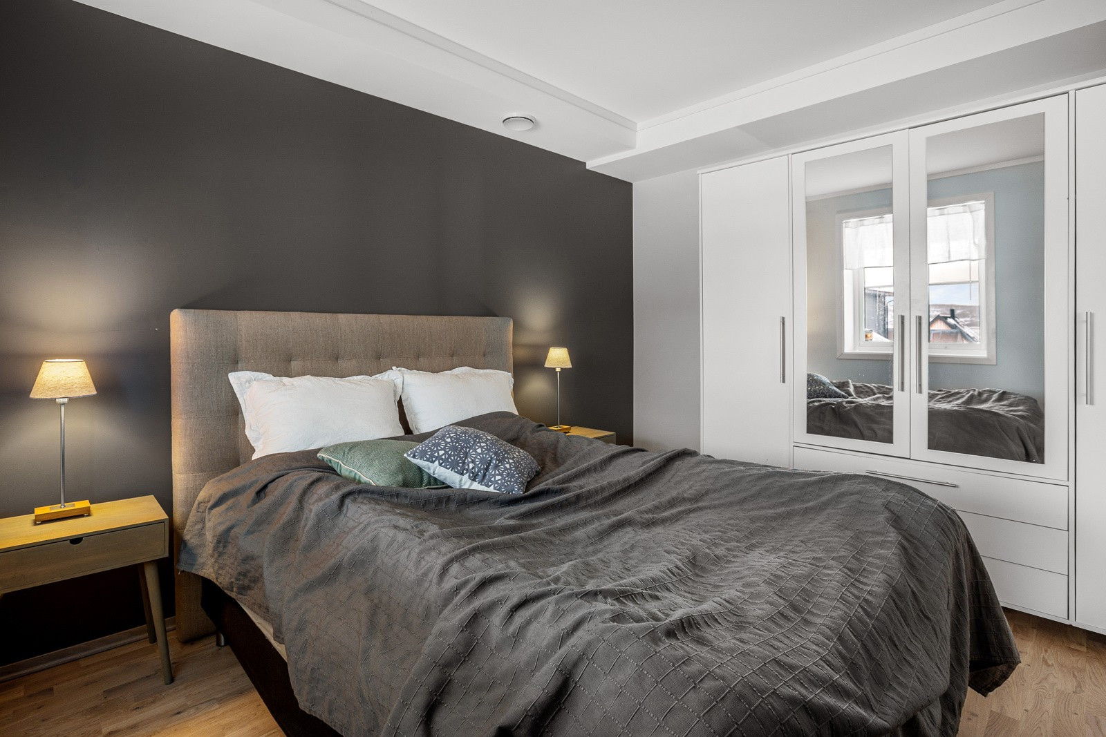 Leilighetens første soverom er av god størrelse med plass til stor seng med tilhørende nattbord.