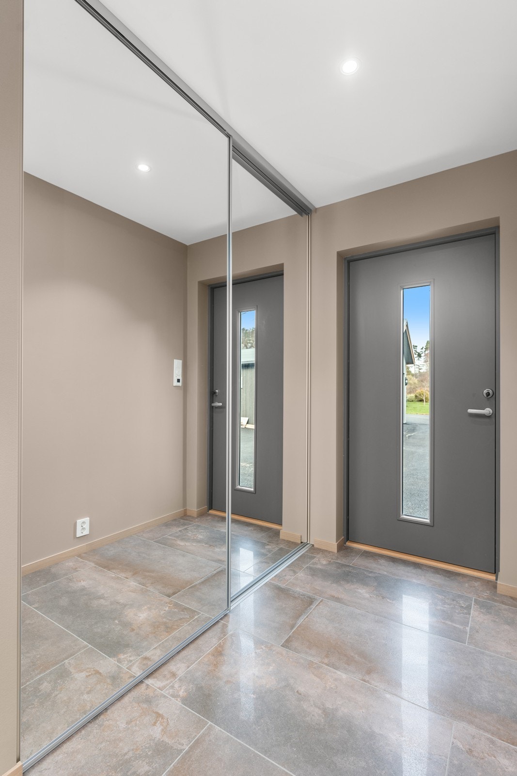 Flislagt inngangsparti med varme i gulv og skyvedørsgarderobe i speil Galleribilde