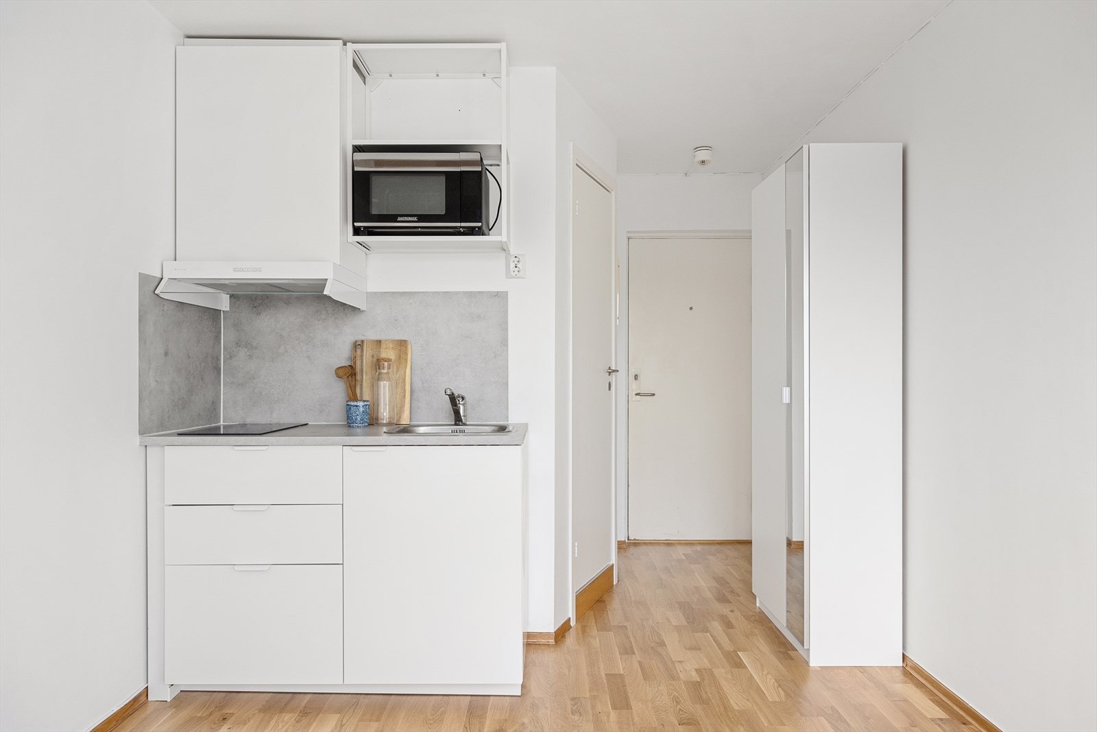 Kjøkkeninnredningen består av hvite, glatte fronter og benkeplate av laminat med nedfelt vask- og skyllekum. Galleribilde
