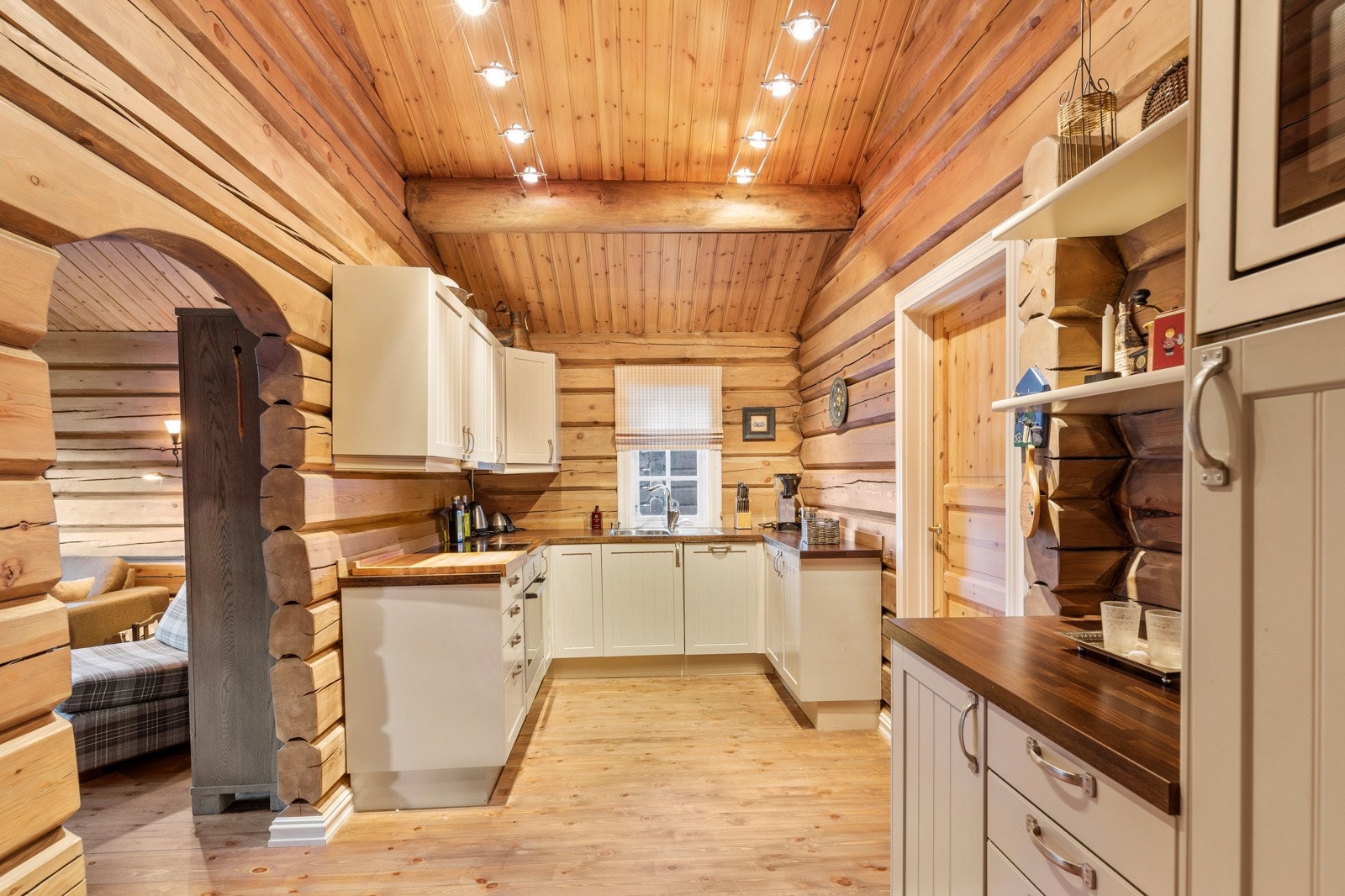 Kjøkkenet har en romslig, U-formet innredning med benkeskap, høyskap og overskap med hvite, profilerte fronter Galleribilde