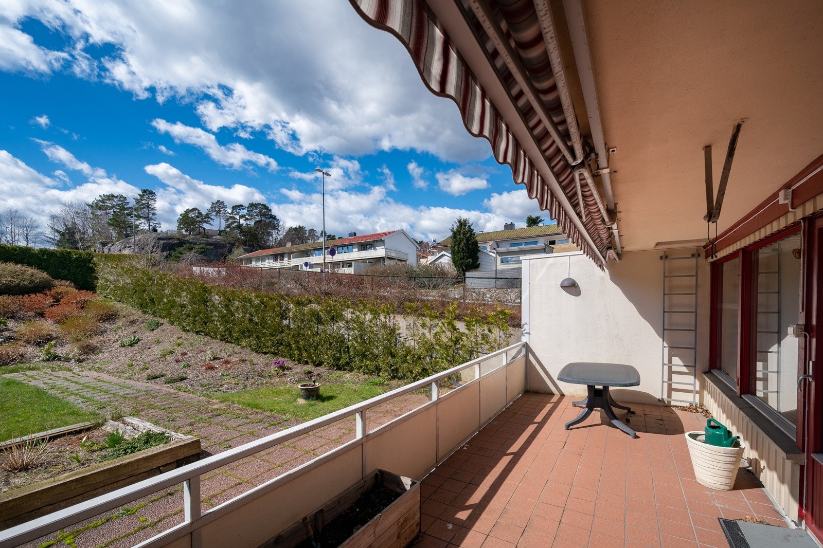 Terrasse på 18 m² har flislagt gulv, takoverbygg og stor markise Galleribilde