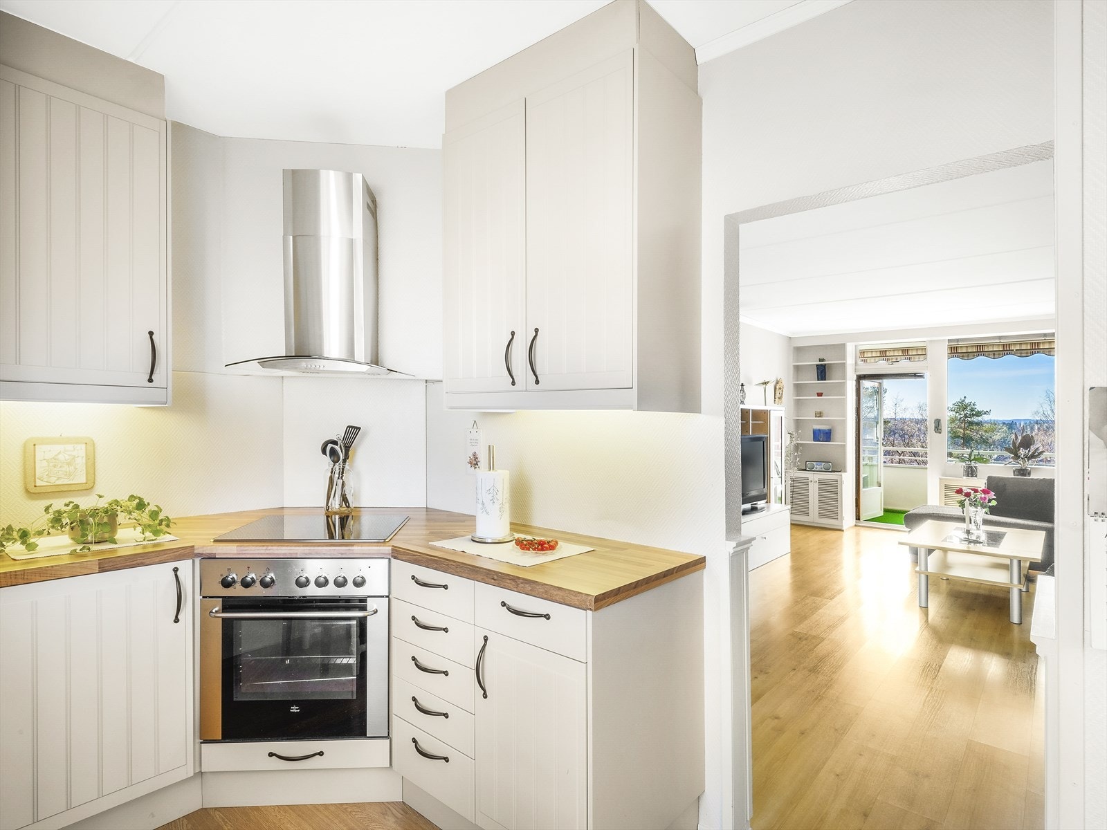 Integrert komfyr og platetopp, med vegghengt kjøkkenhette i stål. Galleribilde