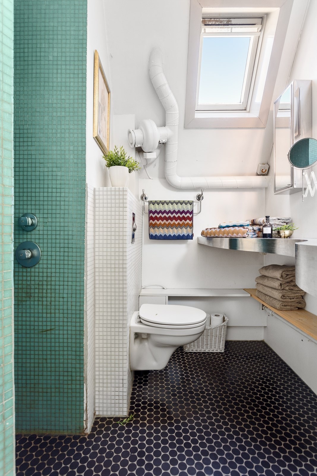 Badet er utstyrt med vegghengt wc, dusj i hjørne og servant. Galleribilde