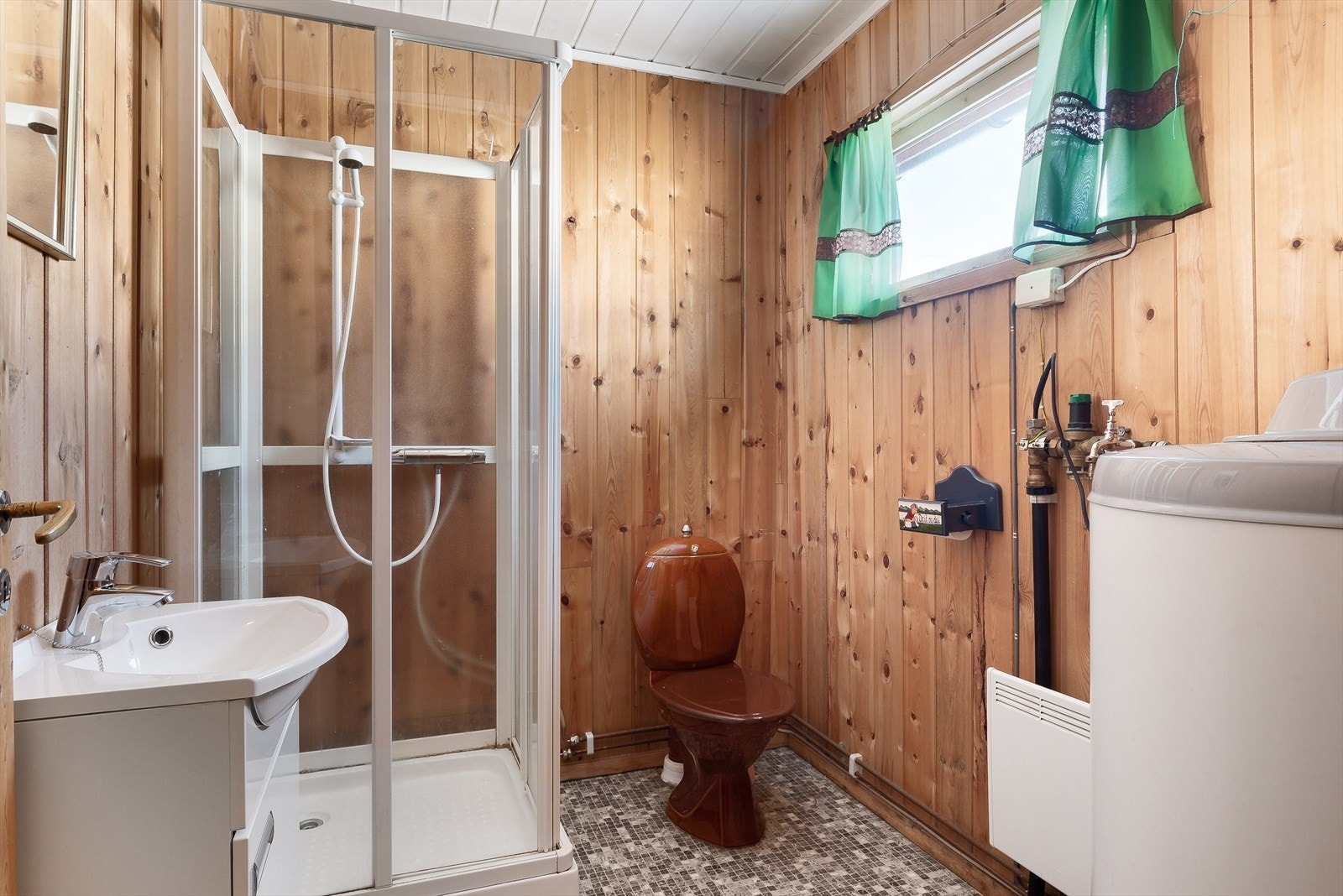 Det ca. 4 kvm. store badet er innredet med panelovn og flismønstret våtromsbelegg på gulvet. Galleribilde