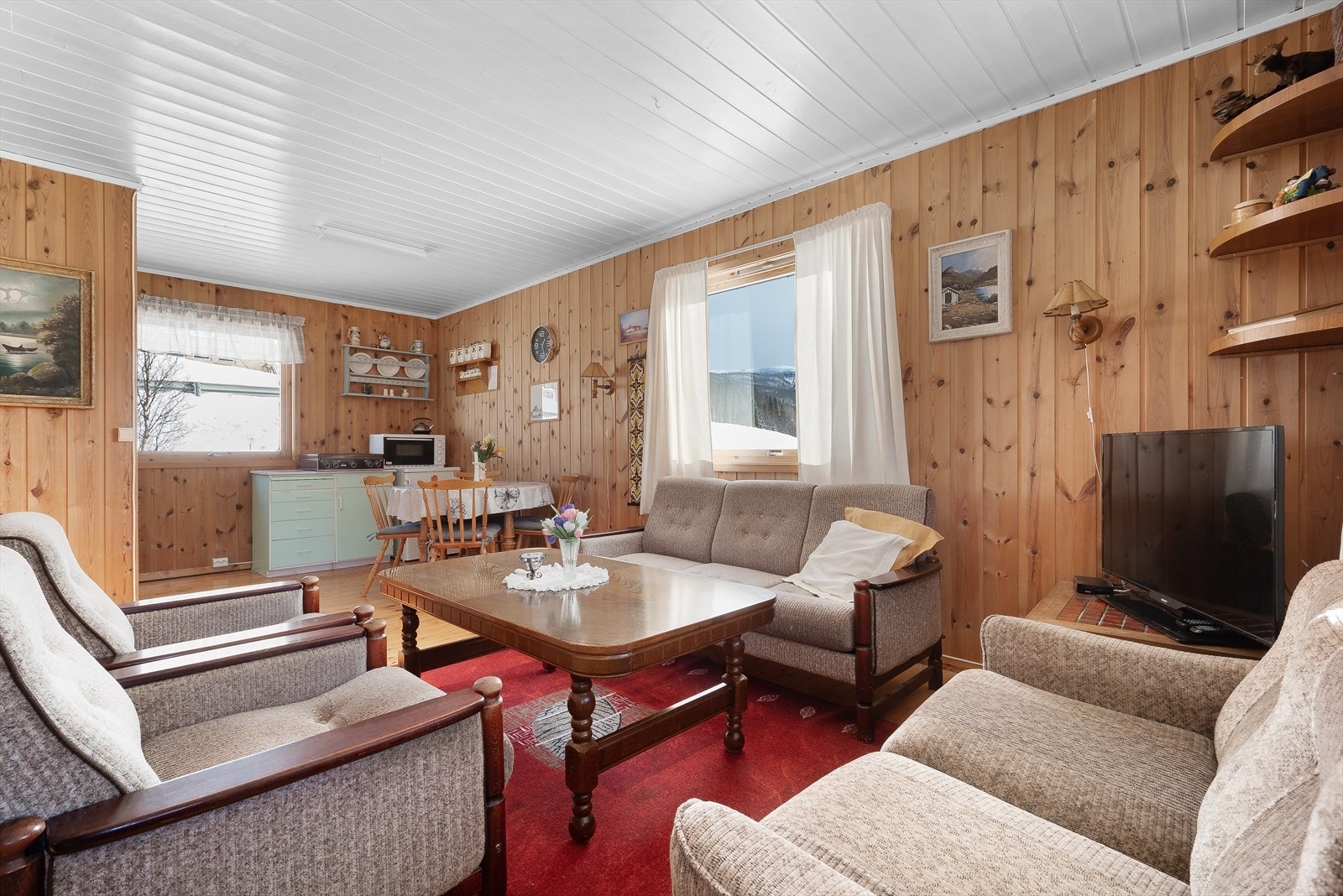 Fritidseiendommen har en varm atmosfære med furugulv og trepanel på veggene. Galleribilde