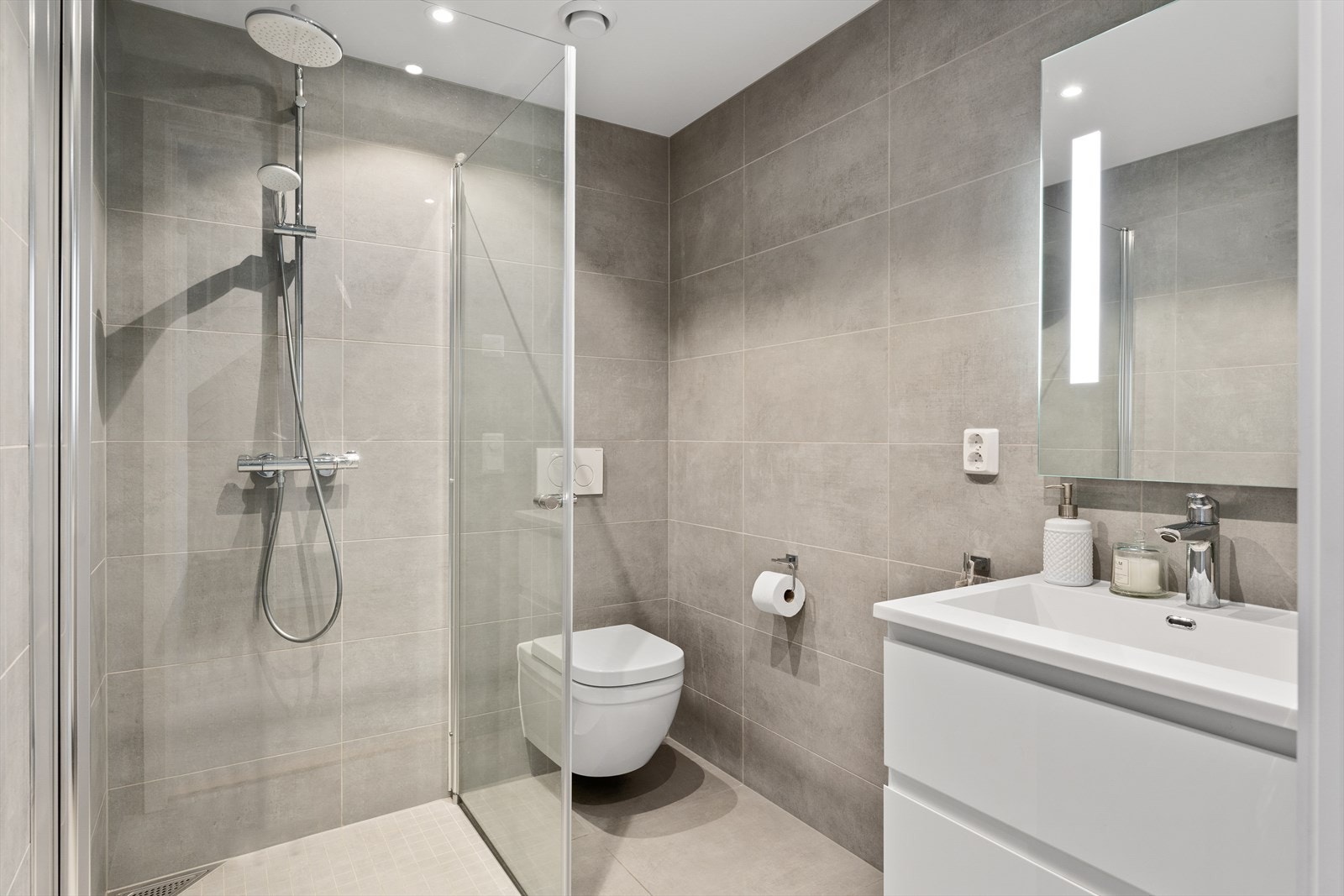 Badet er innredet med servantskap med heldekkende servant, speilskap med integrert lys. Dusjhjørne med innadslående dusjdører og veggmontert wc. Galleribilde