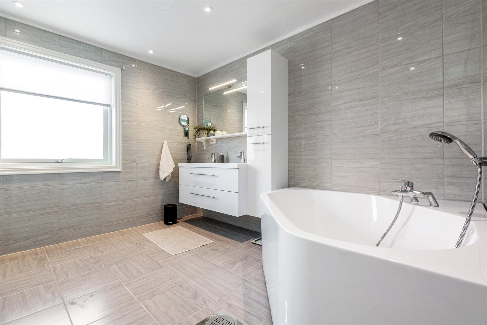 Badet har innredning med to nedfelte servanter, toalett, dusjkabinett og badekar Galleribilde