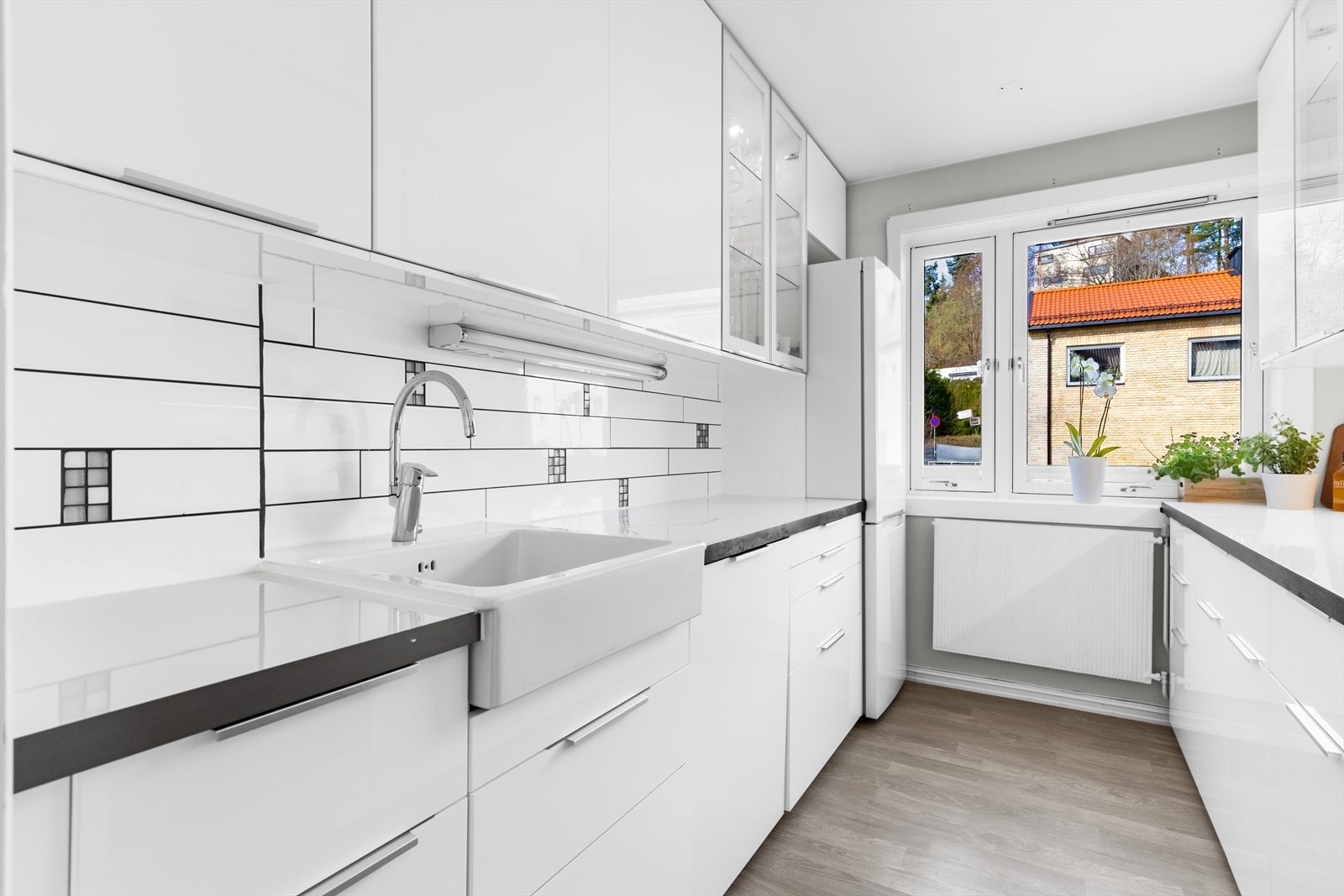 Pene, lyse fronter i høyglanset utførelse. Enkelte glassfronter i overskap. Laminat benkeplate med kum i porselen. Galleribilde