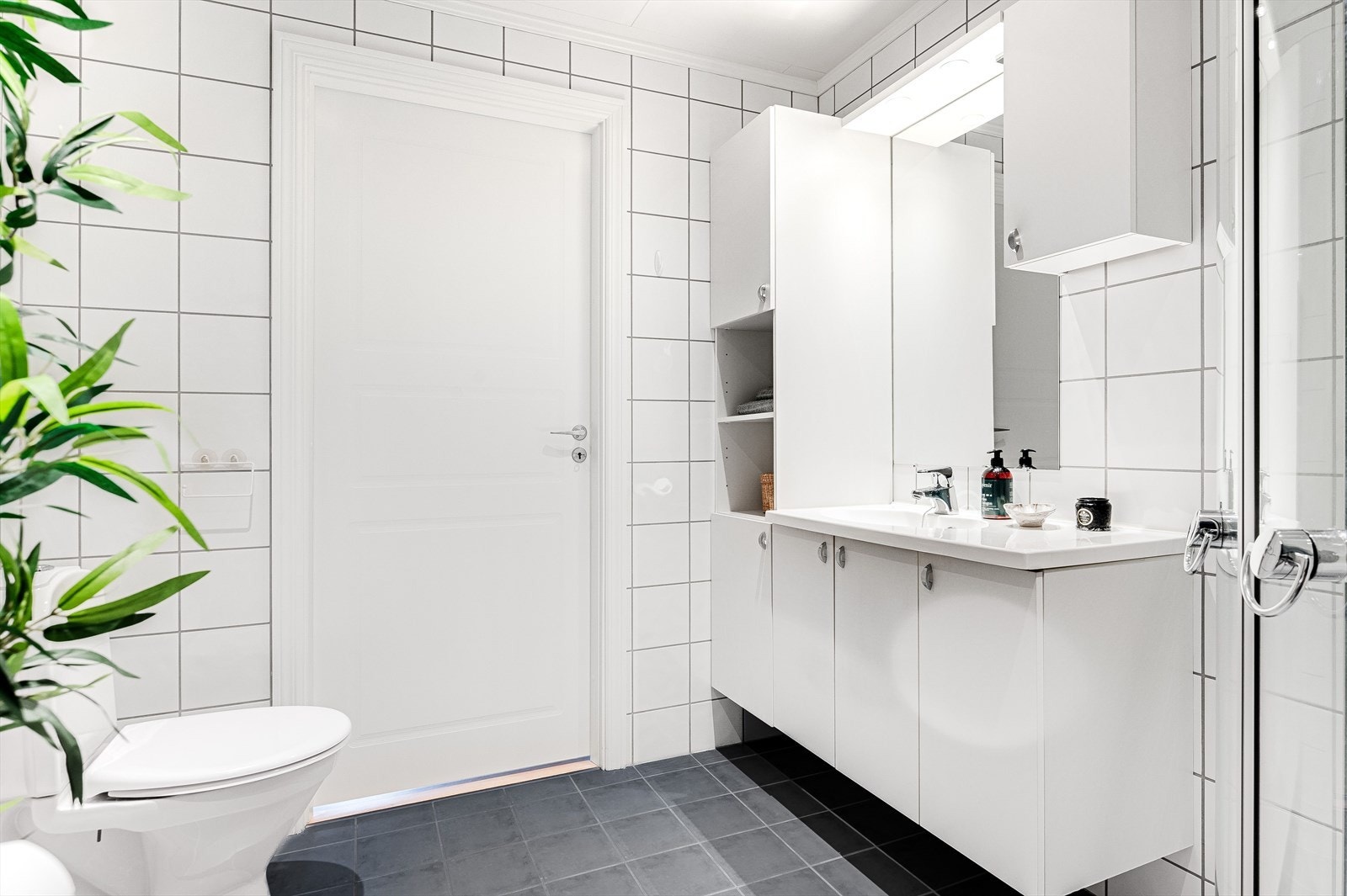 Baderommet er også utstyrt med dusjhjørne med innfellbare glassdører, gulvstående toalett og opplegg for vaskemaskin. Galleribilde