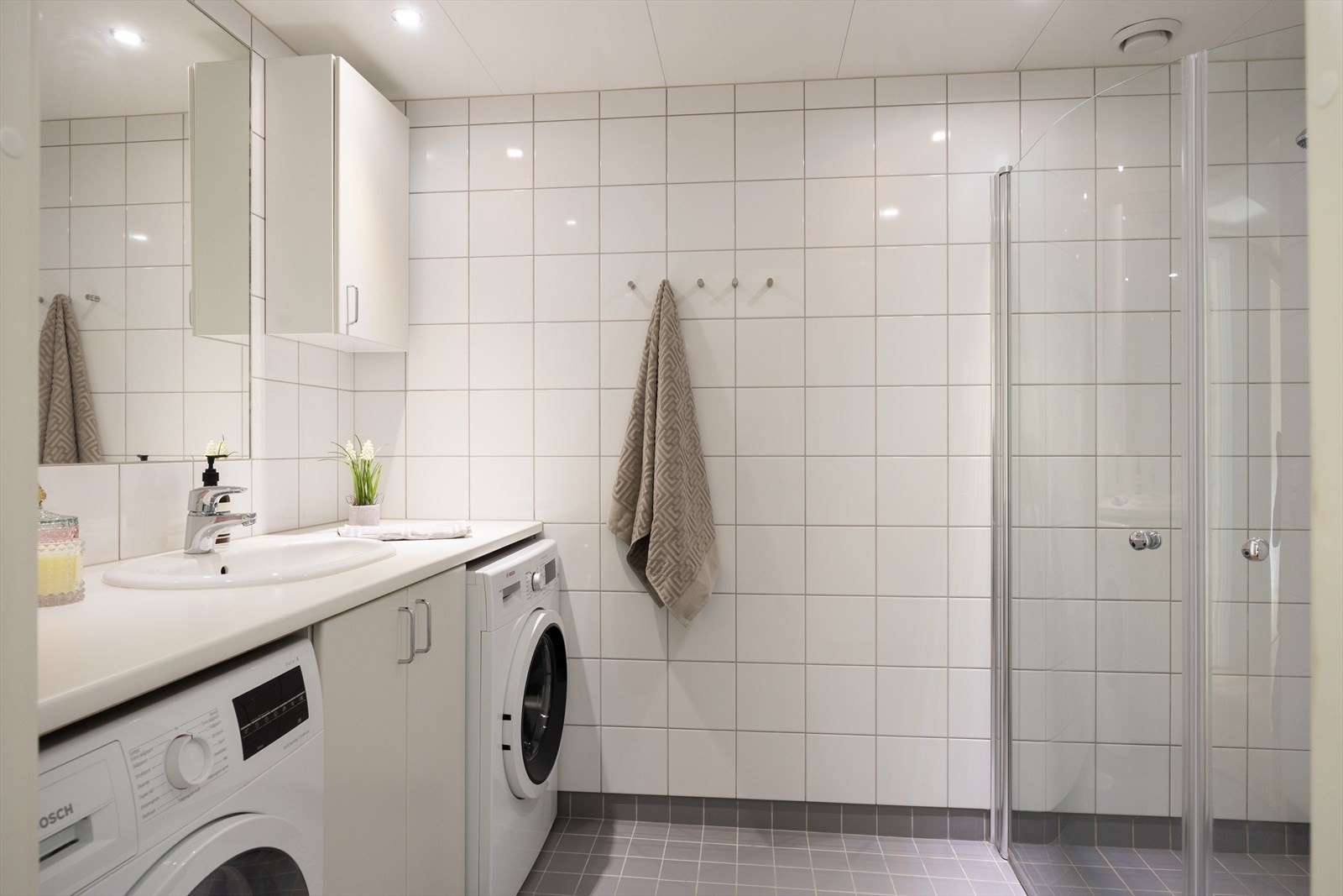 Lekkert flislagt baderom med elektrisk gulvvarme og opplegg for vaskemaskin. Galleribilde