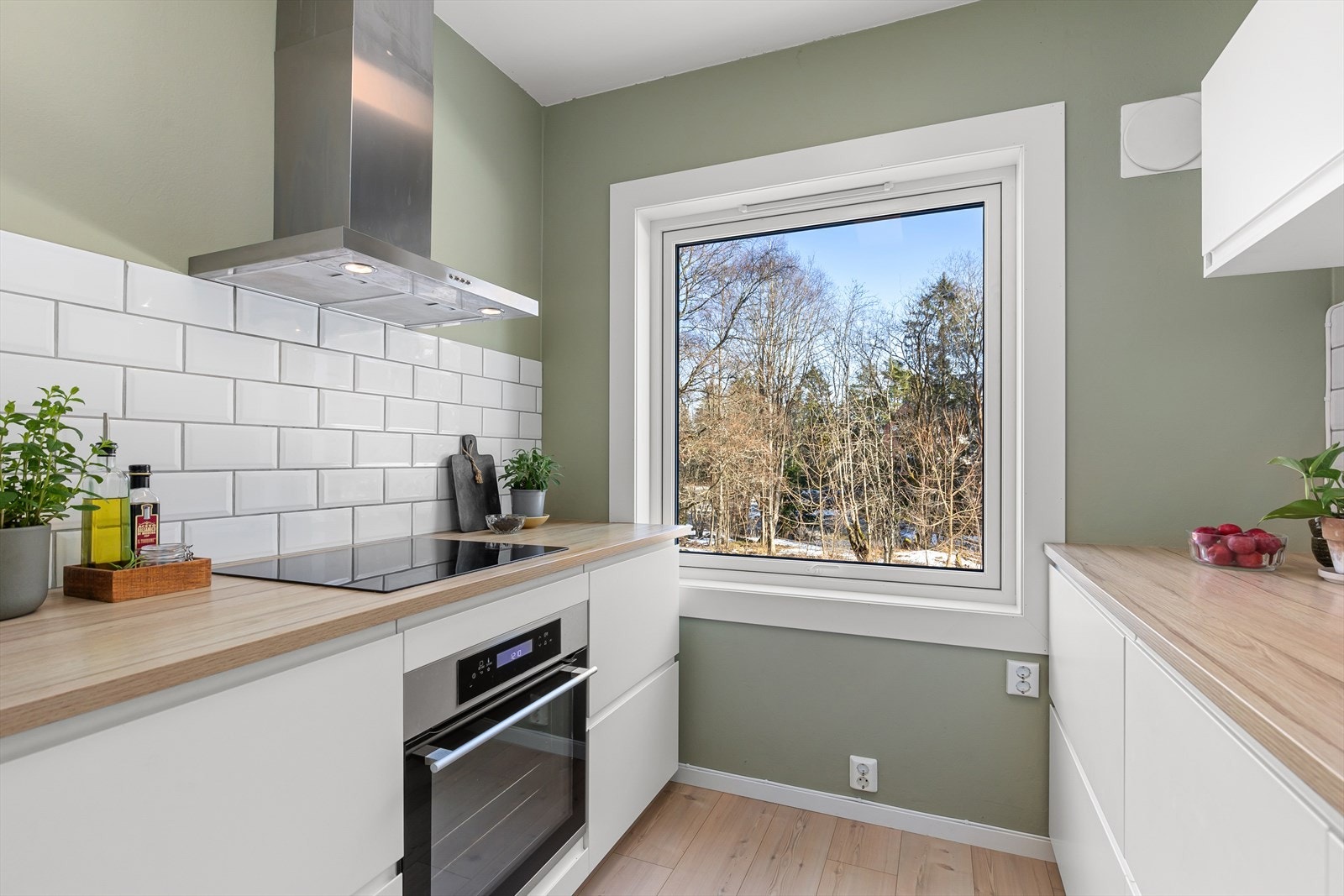 Stort vindu som slipper inn morgensolen med utsikt til platting og skogholt. Galleribilde
