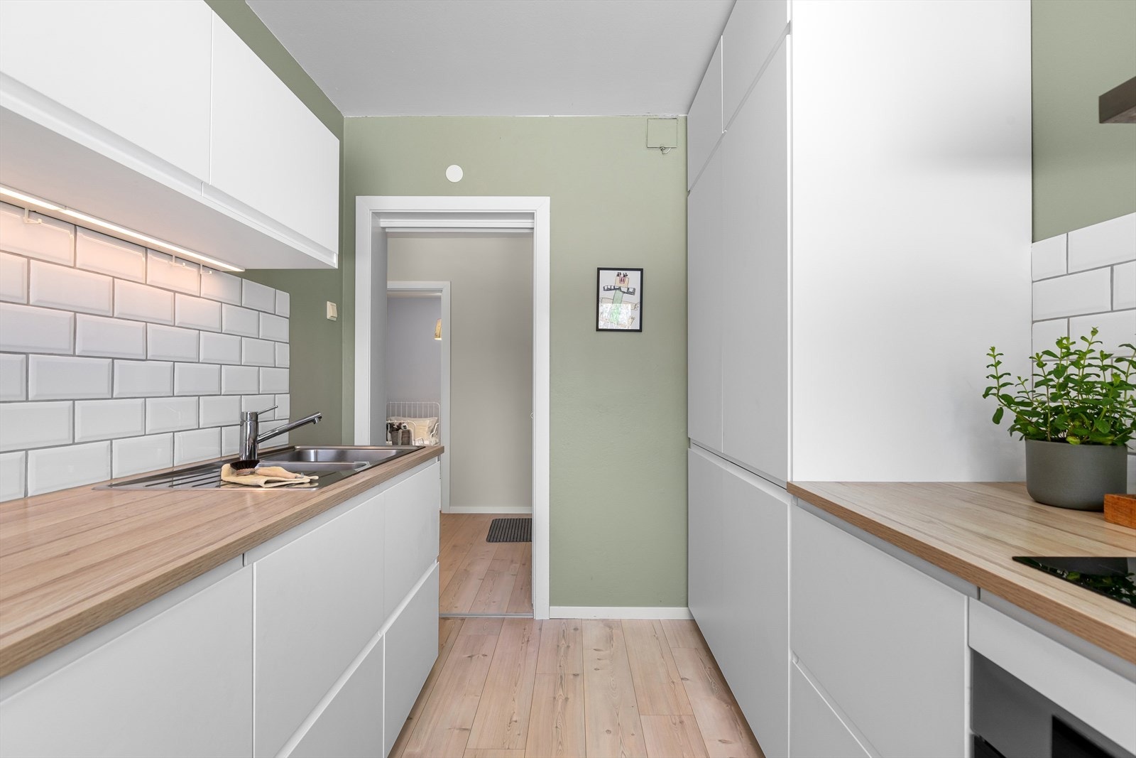 Lekre keramiske fliser over benkeplater, smart belysning under overskapene, samt separate kjøleskap og fryseskap i full høyde. Galleribilde