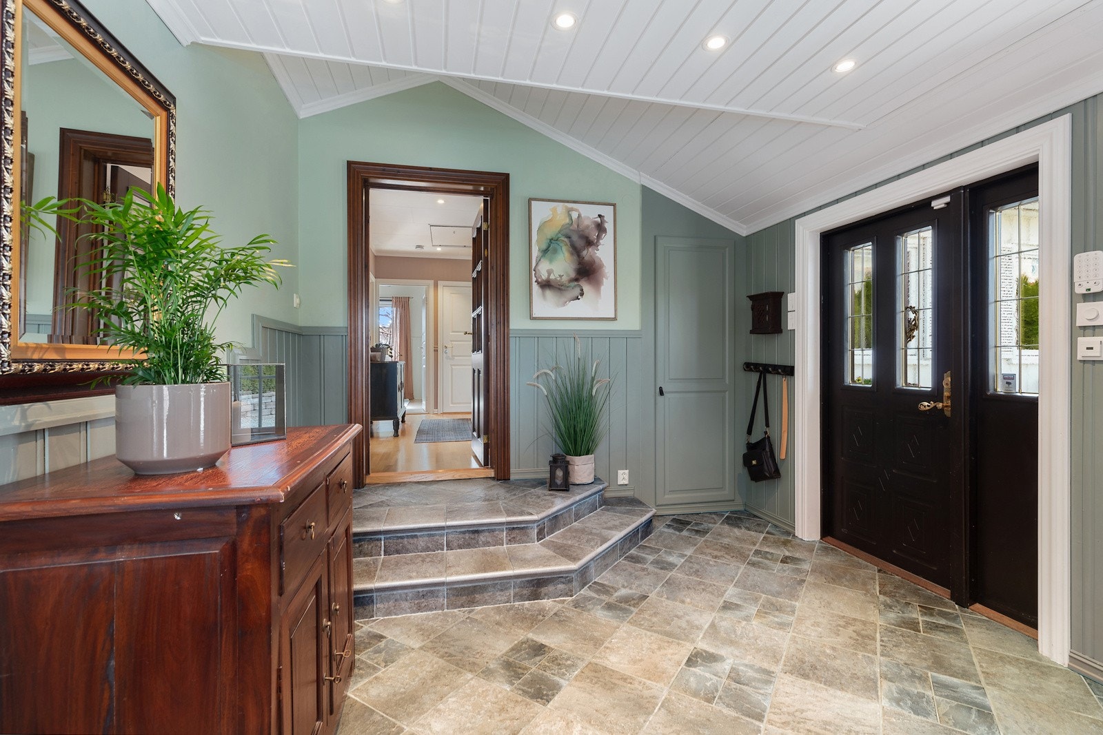 Romslig hall med nivåforskjell opp til resten av boligen Galleribilde