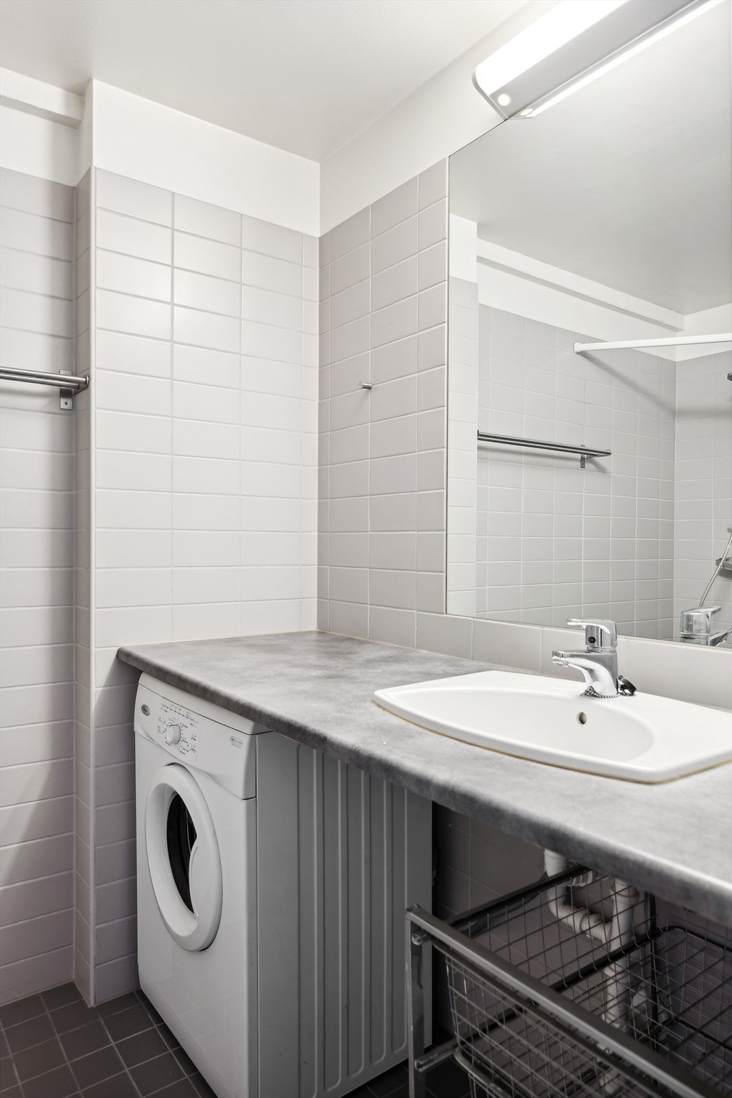 Baderomsinnredningen er bestående av laminat arbeidsbenk med nedfelt servant, innfliset speil, gulvmontert klosett, åpen dusjløsning med forheng og opplegg for vaskemaskin. Det er mekanisk avtrekk fra baderommet. Galleribilde