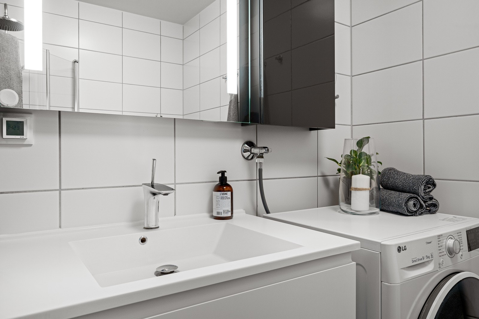 Servantinnredning med speil, vegghengt toalett og opplegg for vaskemaskin. Galleribilde