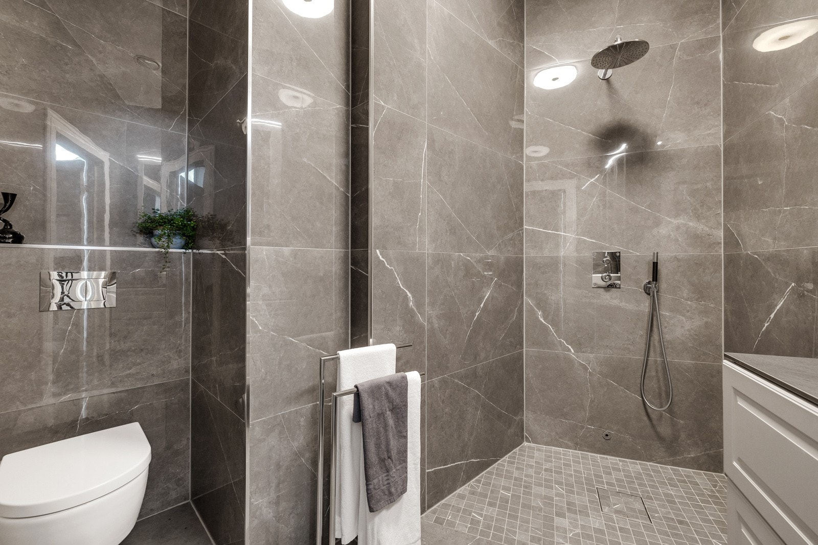 Badet består av servant over innredning, åpen dusjløsning, speilskap og vegghengt toalett Galleribilde