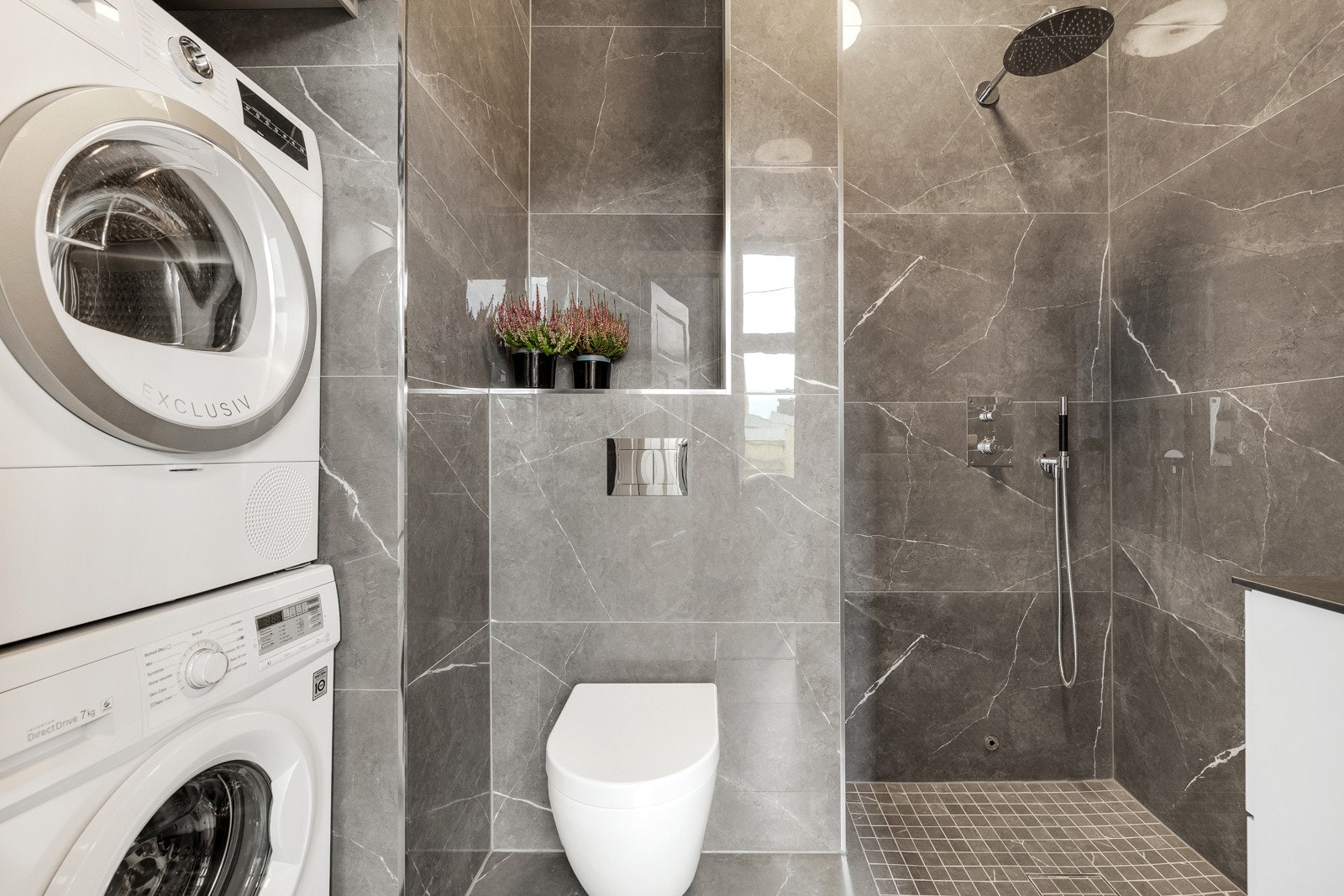 Baderommet består av servant over innredning, speil med lys, åpen dusjløsning og vegghengt toalett. Galleribilde