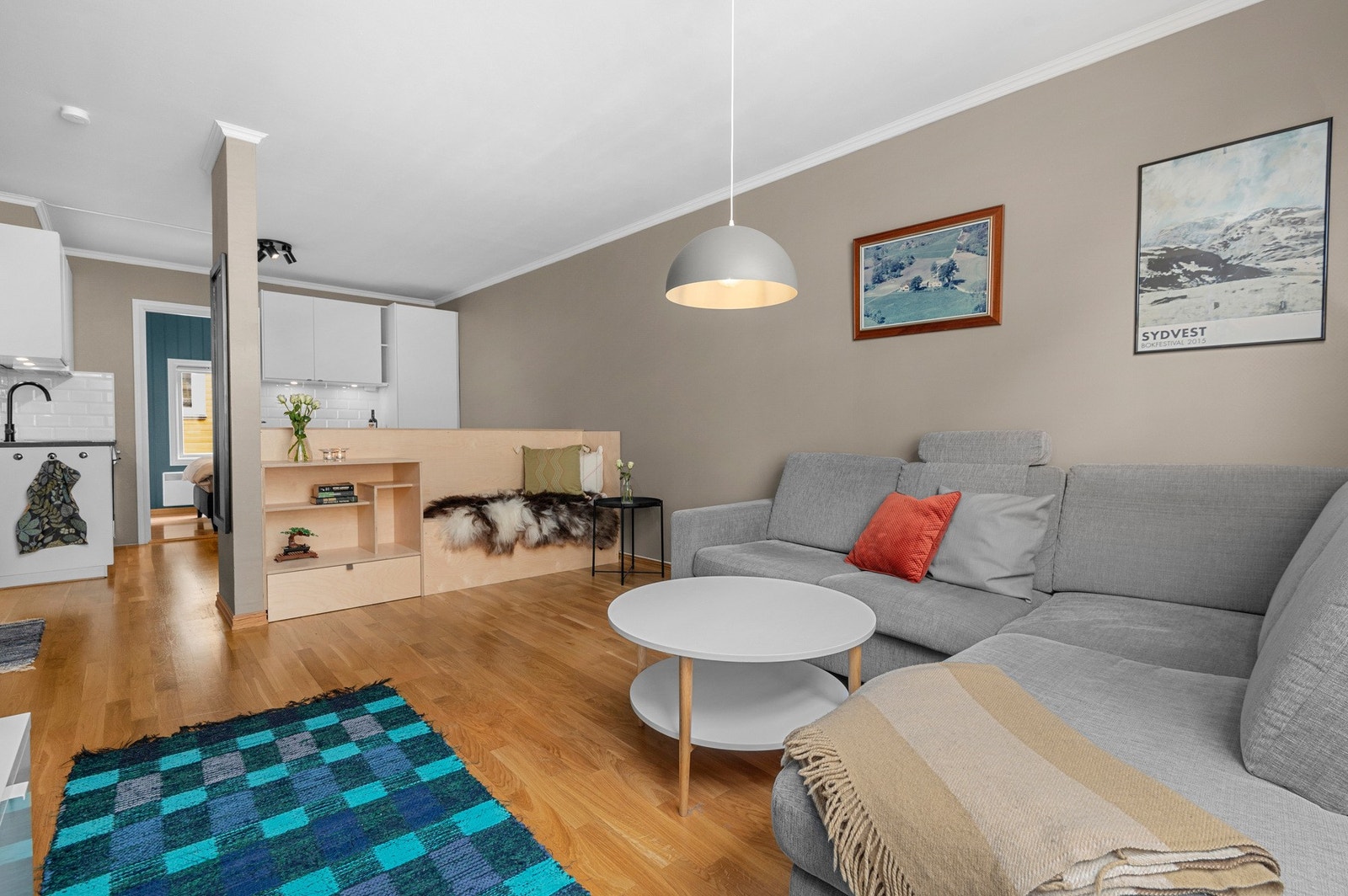 Pent oppusset stue med plassbygd møbel som deler av for kjøkkenet. Galleribilde