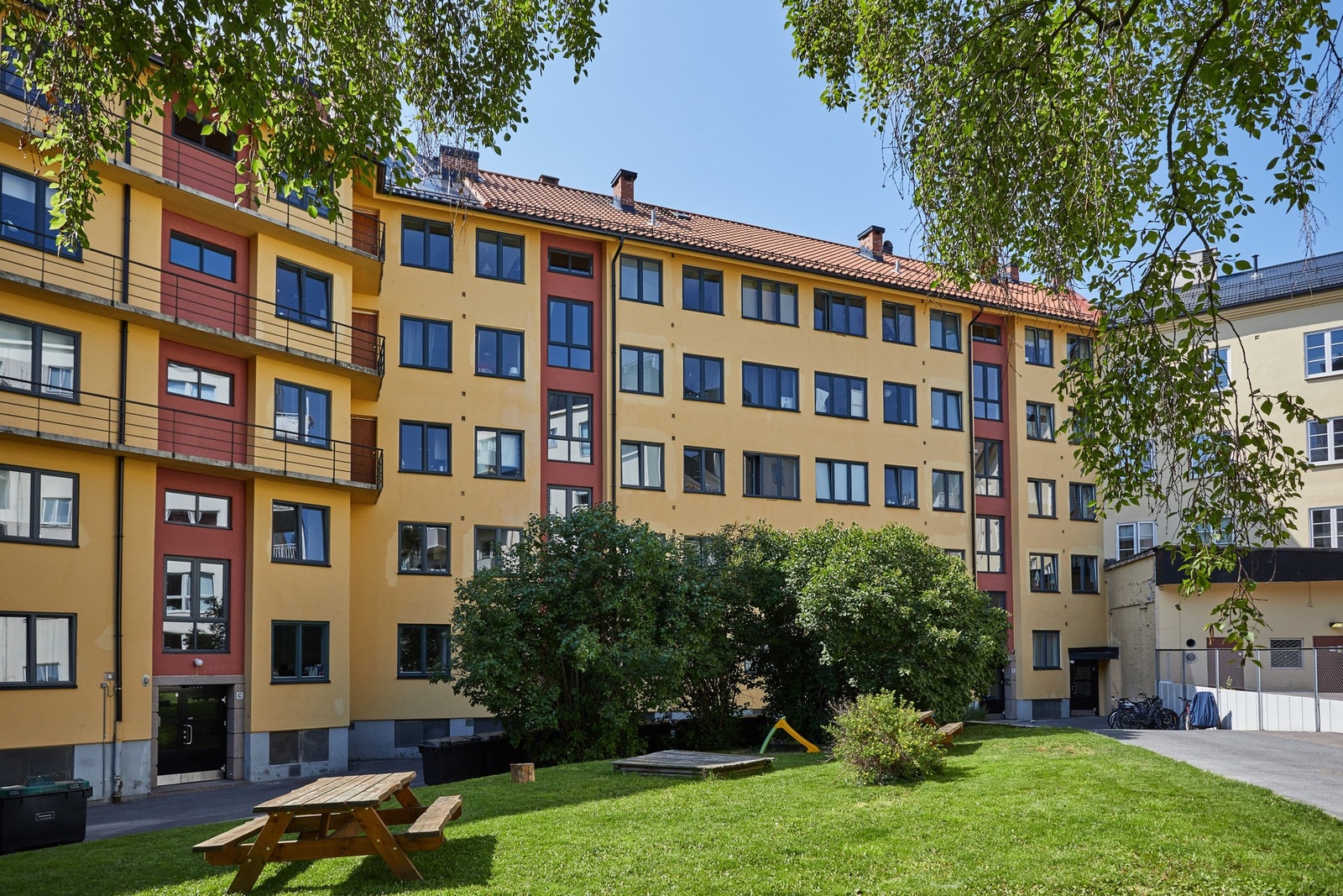 Felles bakgård for borettslaget opparbeidet med blant annet asfalterte internveier, gressplen, sittegrupper,sykkelstativer og diverse beplantning. Galleribilde