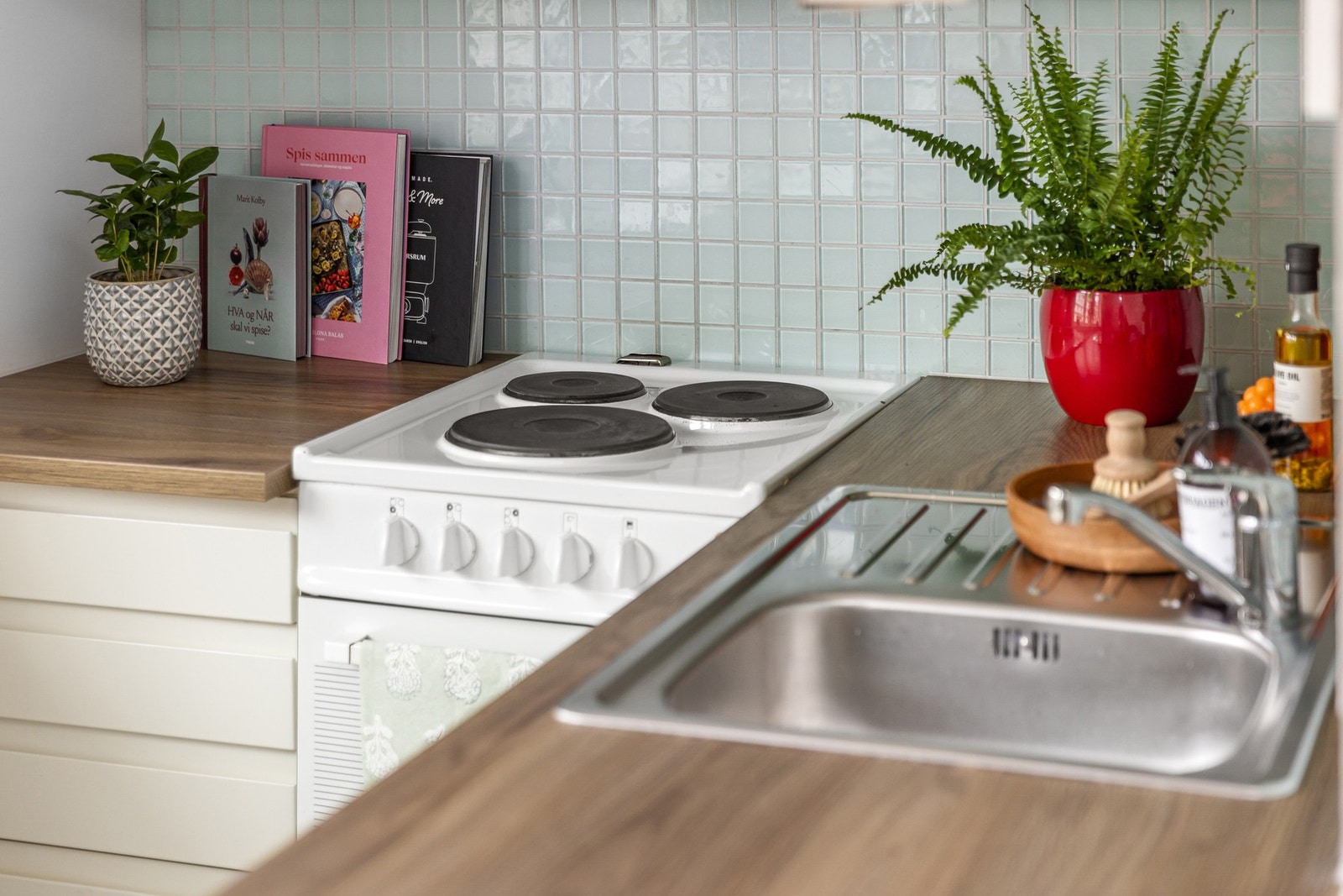 Innredningen har hvite glatte fronter, laminert benkeplate med nedfelt oppvaskkum og fliser i benkeryggen. Galleribilde