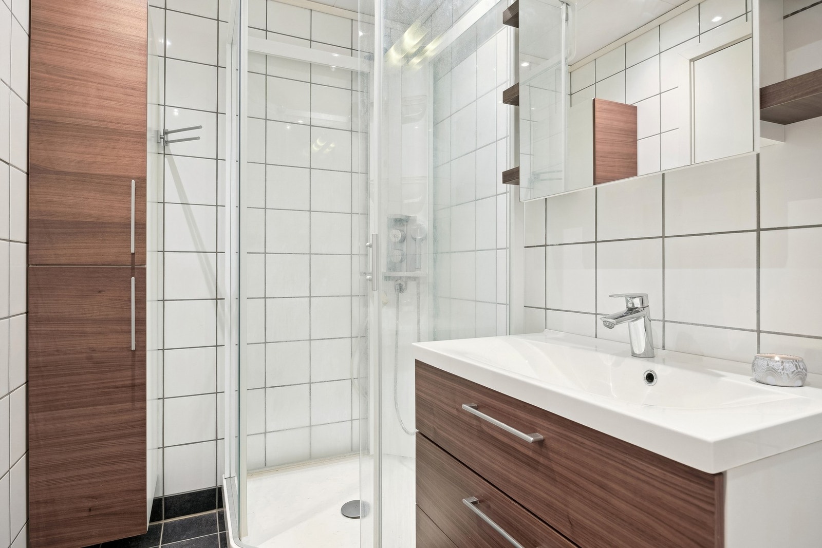 Tidløs baderomsinnredning, med både veggskap og speilskap. Badet er videre innredet med et dusjkabinett og har vegghengt wc. Galleribilde
