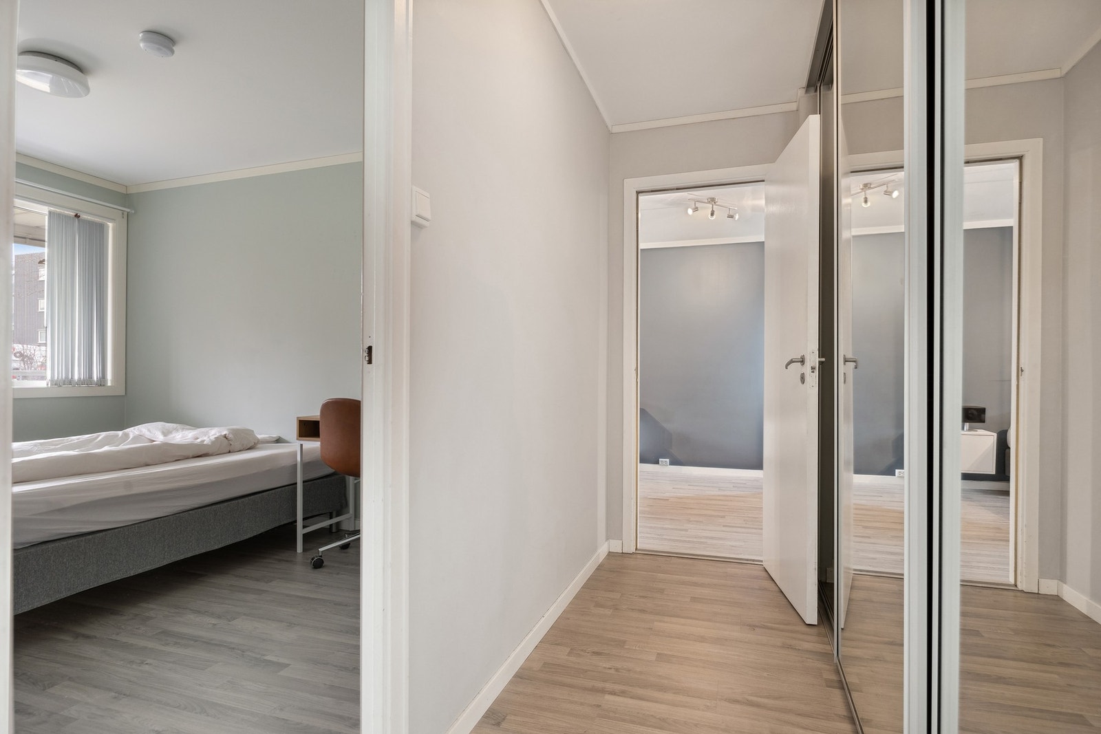 Fra stua har du en praktisk gang med etablert skyvedørsgarderobe som leder deg mot leilighetens to soverom. Galleribilde
