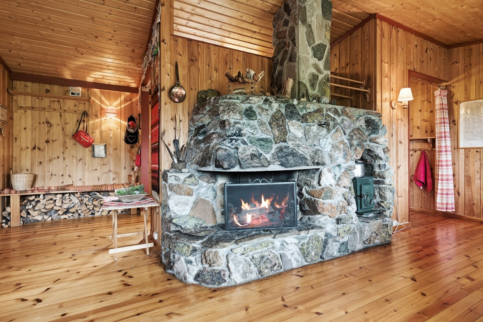 Den flotte, åpne peisen i naturstein gir lun varme på kalde dager, i kombinasjon med ved- og panelovn. Galleribilde