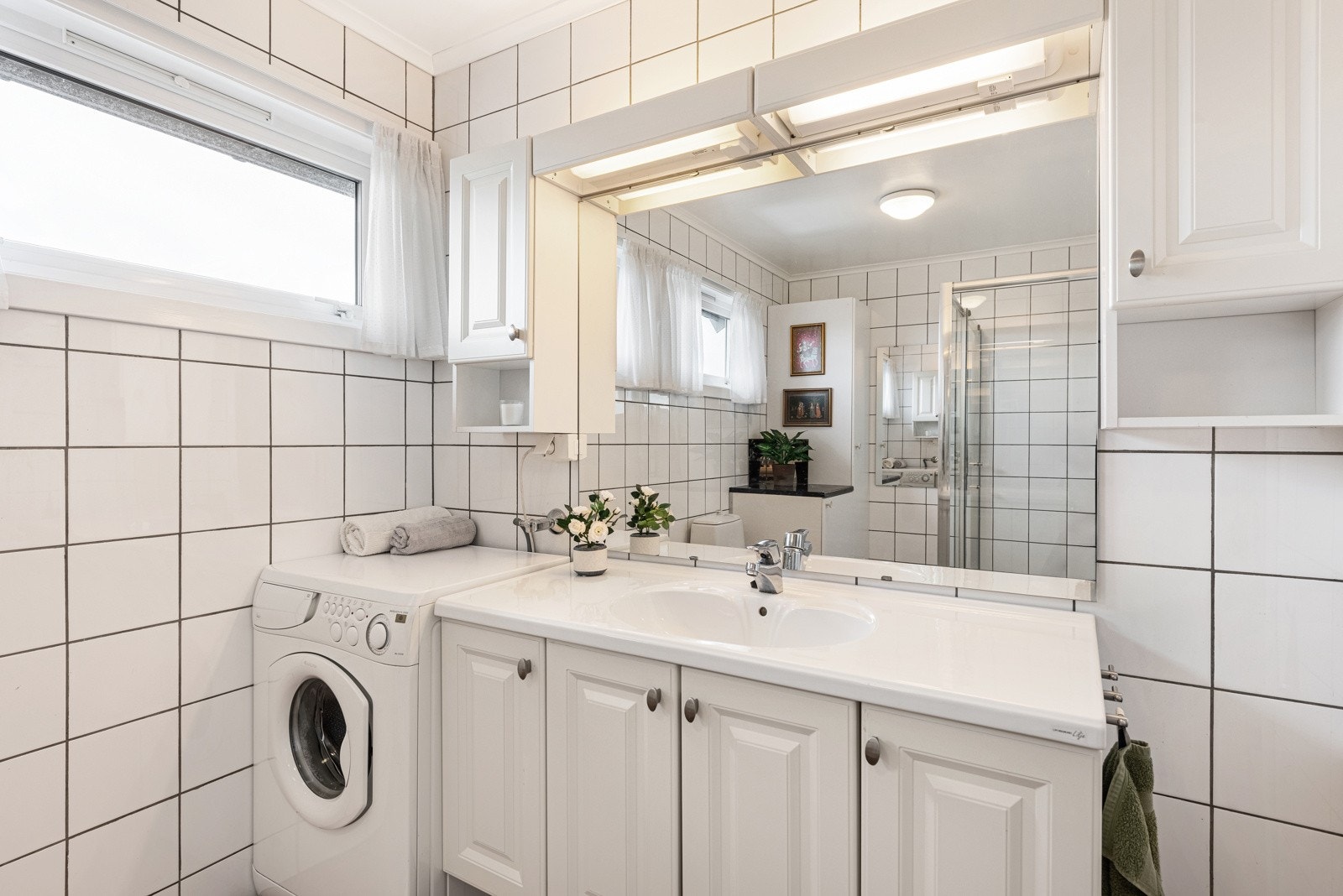 Det er gulvvarme og opplegg for vaskemaskin, og badet har toalett og et stort dusjhjørne med skyvedører. Galleribilde