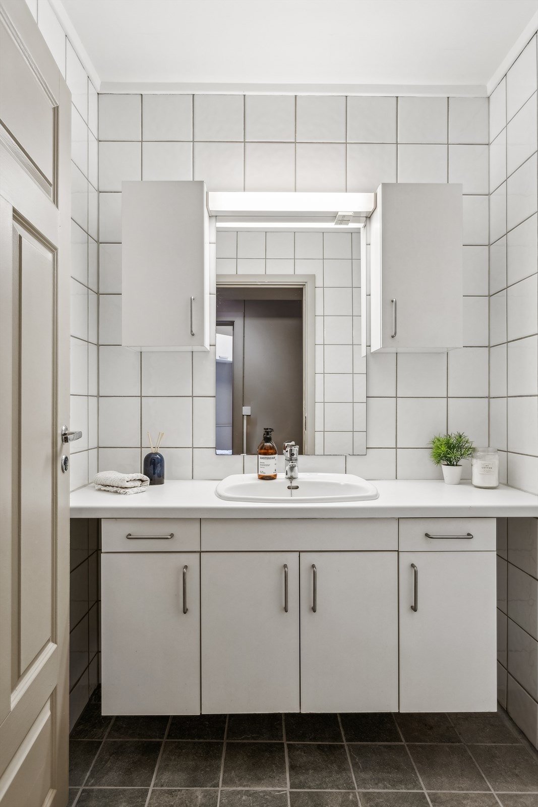 Fint flislagt baderom med vegghengt underskap, speil og overskap Galleribilde