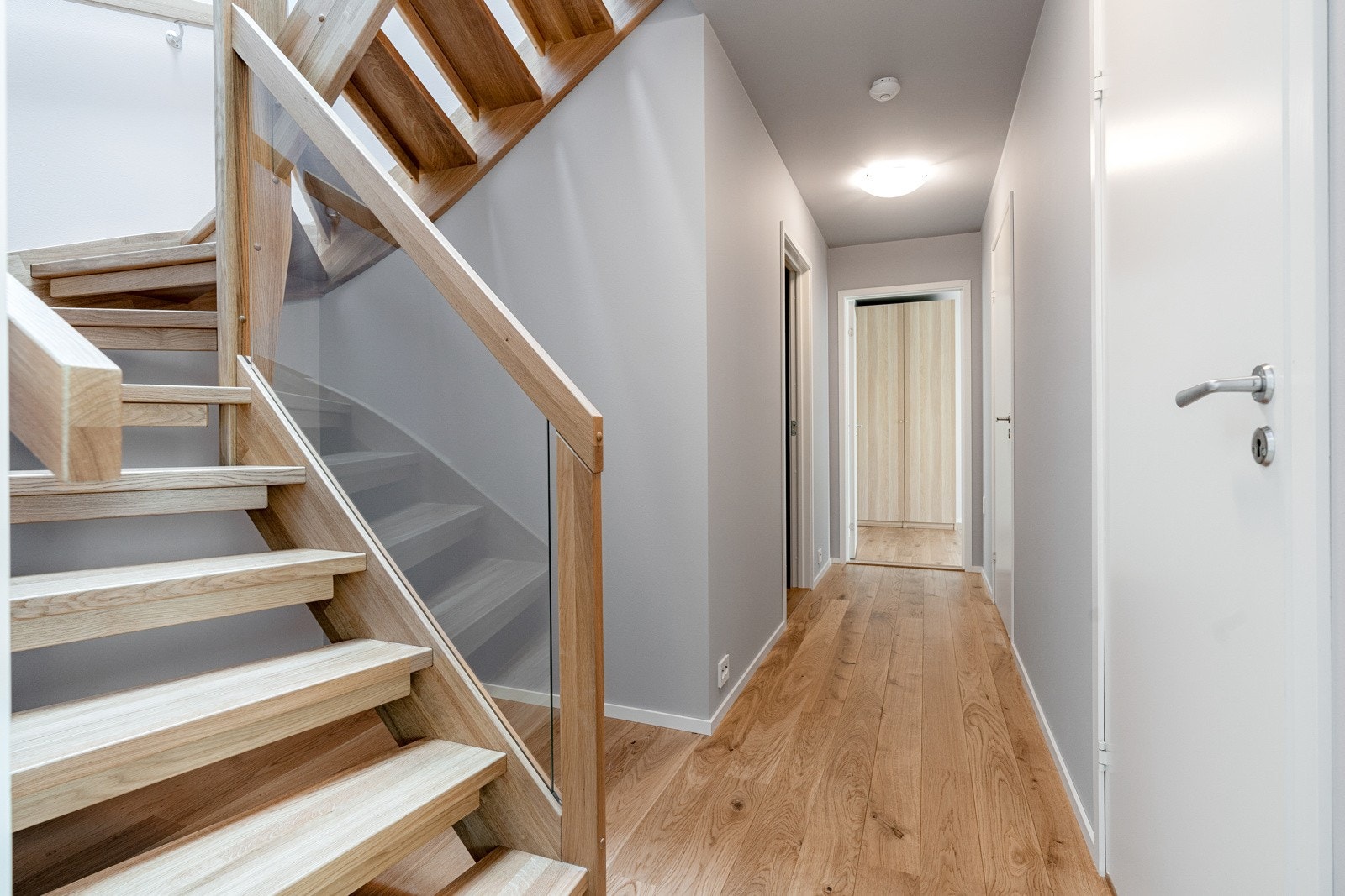 Hagen trapp med trinn og vange i eik samt glass. Trappen passer godt til parkett og fargevalg på veggene. Galleribilde