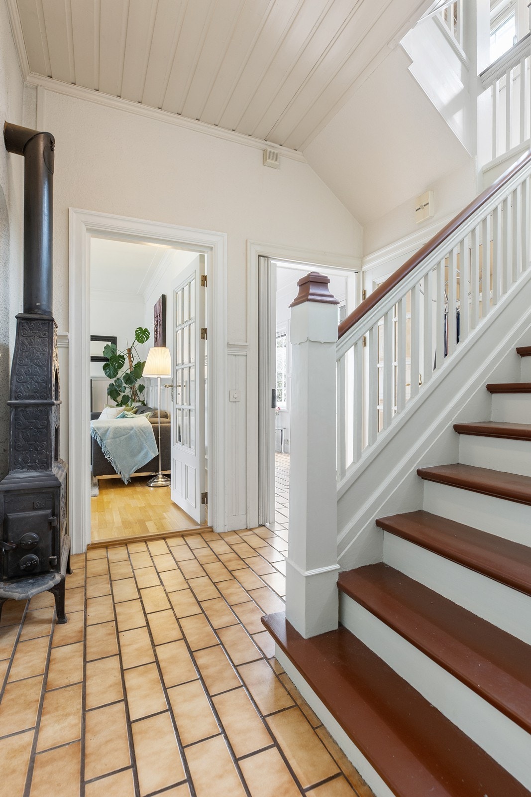 Etasjeovn i hallen. Adkomsten til vinterhagen skimtes bak trappen Galleribilde