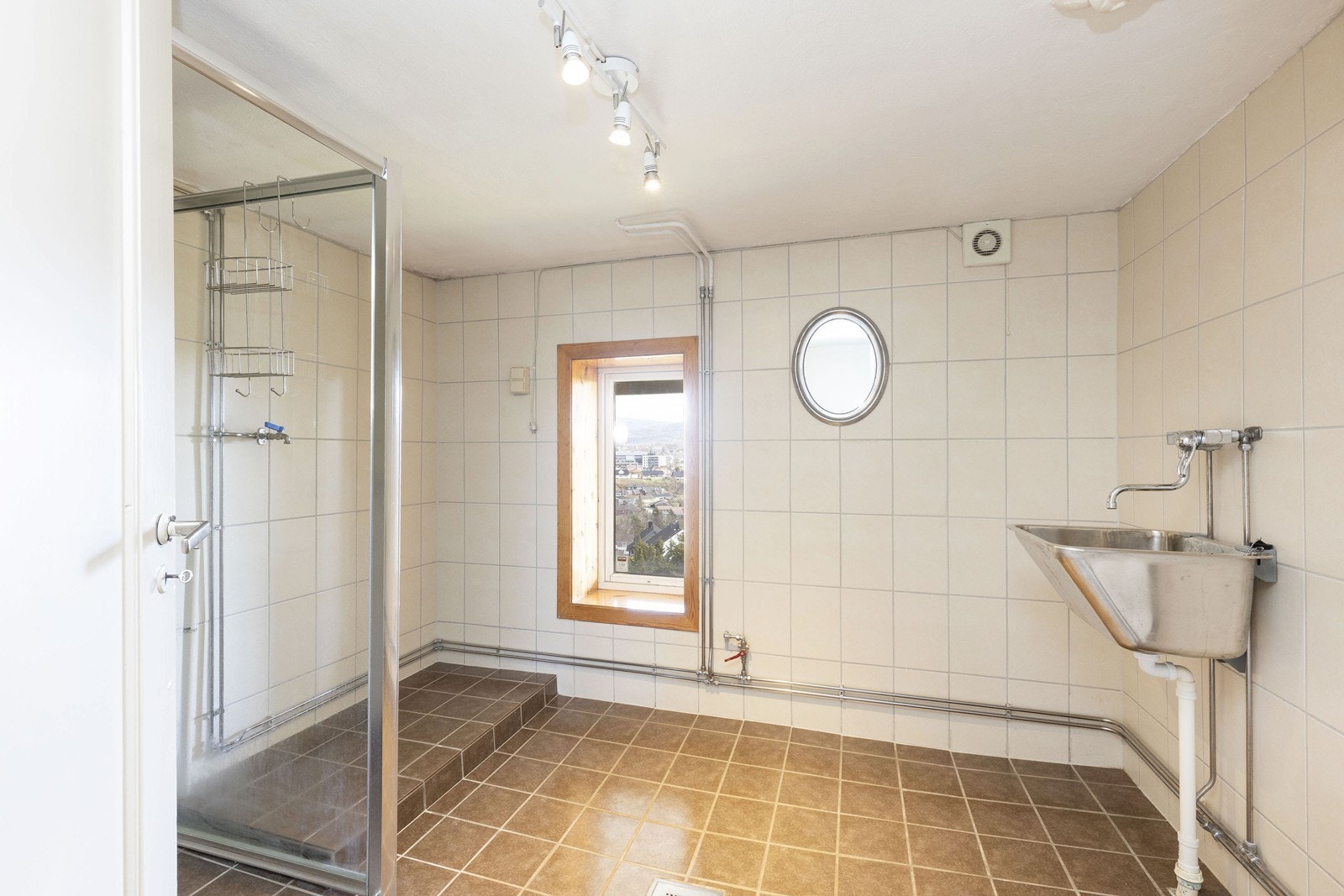 Bad/vaskerom med flis på gulvet, flis på veggene og malt betong i himlingen. Galleribilde