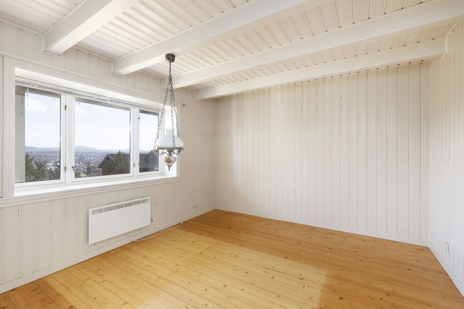 Stue i underetasjen med eldre furugulv og malt panel på veggene og i himlingen. Galleribilde