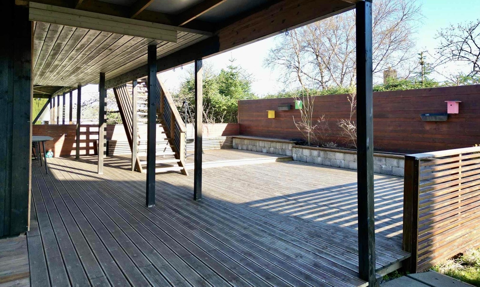 Stor, skjermet terrasse med plassbygde blomsterkasser og benker (foto privat) Galleribilde
