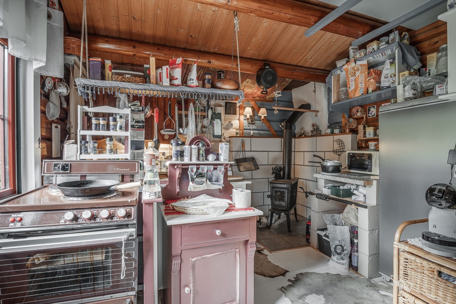 Kjøkkenet i fritidsboligen er av eldre dato og har åpen løsning for hvitevarer. Galleribilde