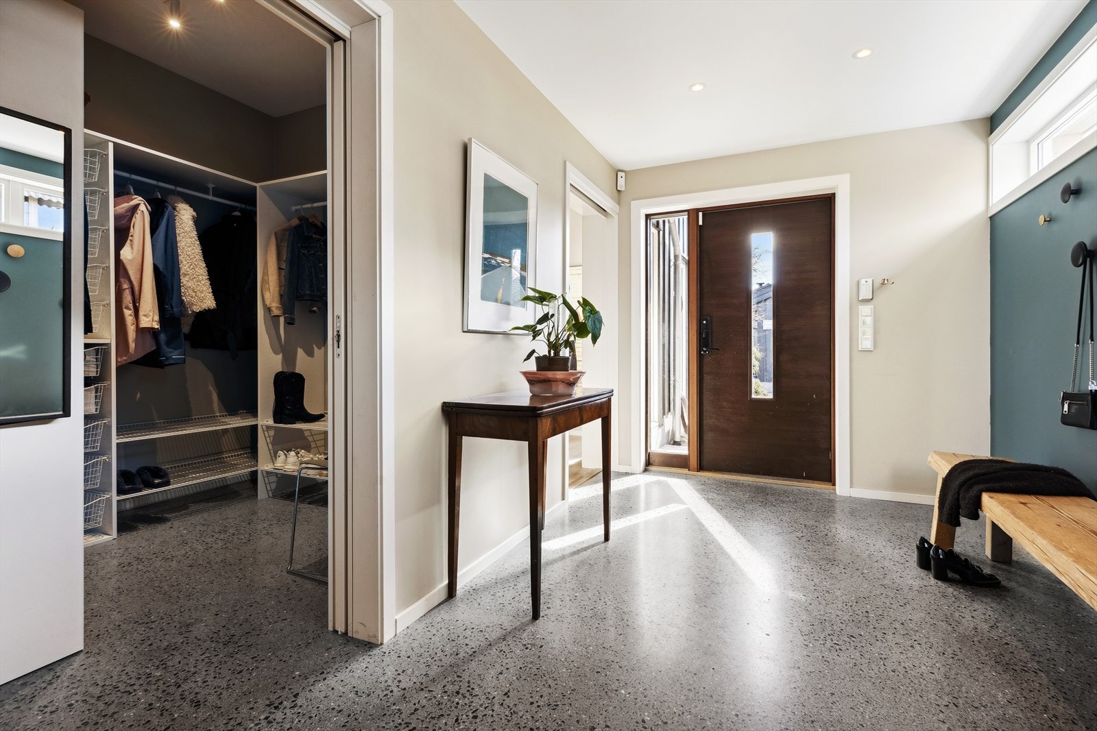 Romslig gang med et solid og stilig gulv av slipt betong. Innenfor er en stor og praktisk garderobe. Galleribilde