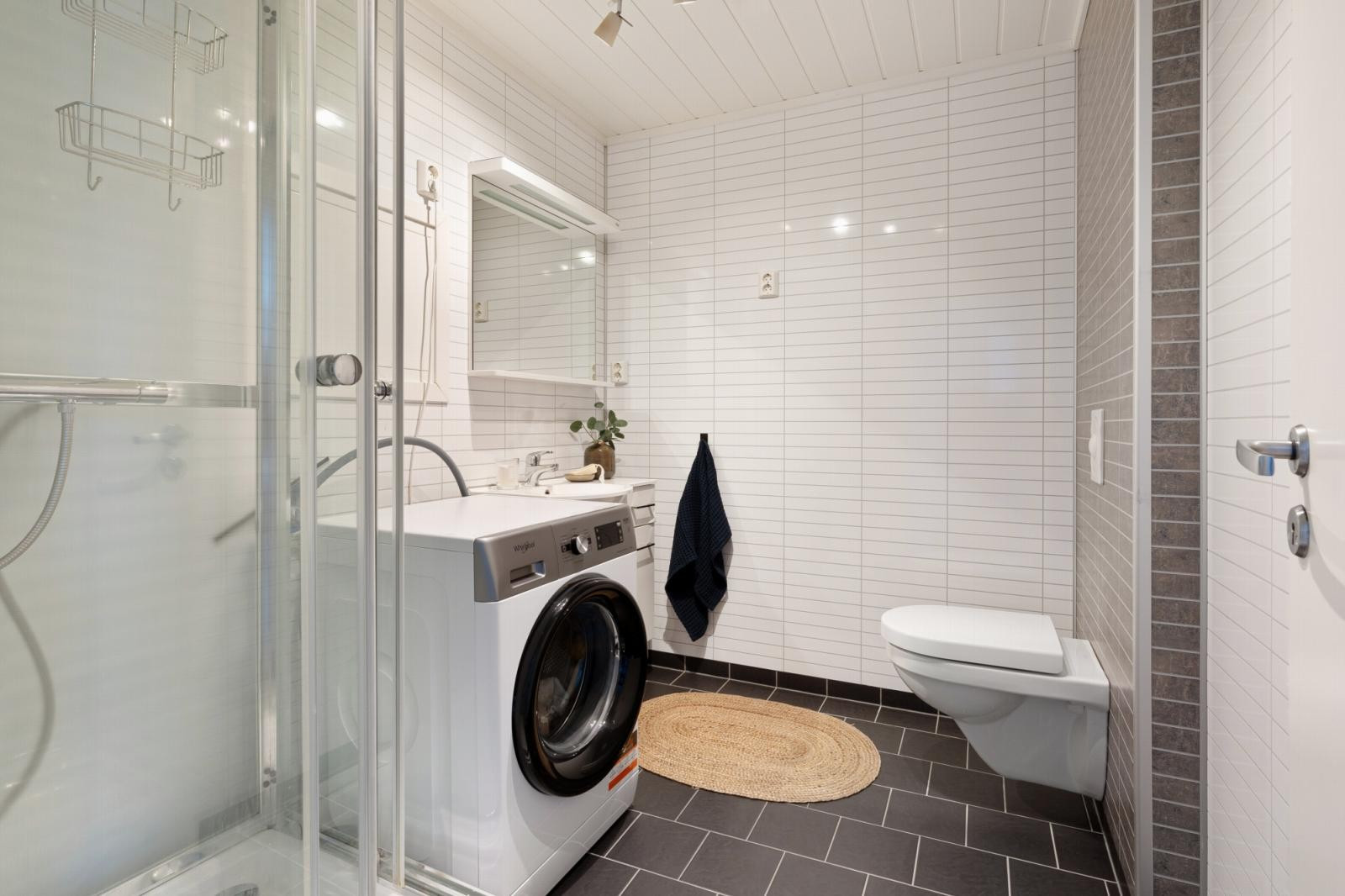 På badet har du vegghengt toalett, dusjkabinett og baderomsinnredning.