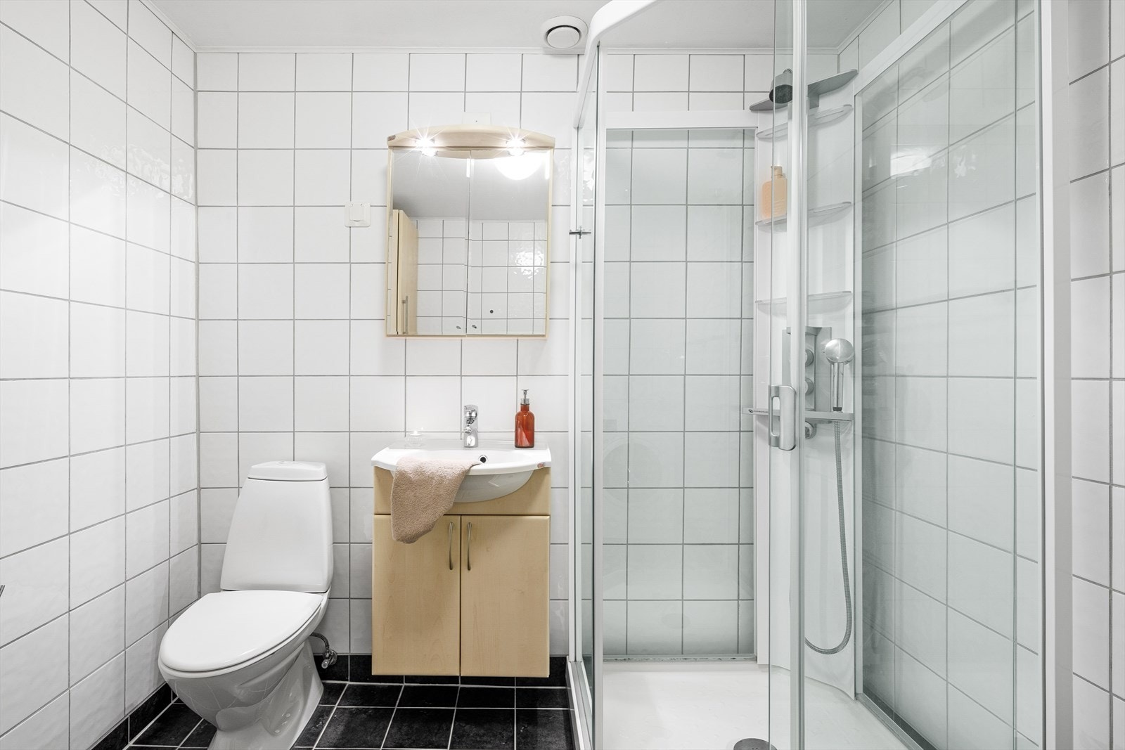 Badet er innredet med servant i baderomsinnredning, toalett og dusjkabinett. Det er opplegg for vaskemaskin og plass til tørketrommel. Galleribilde