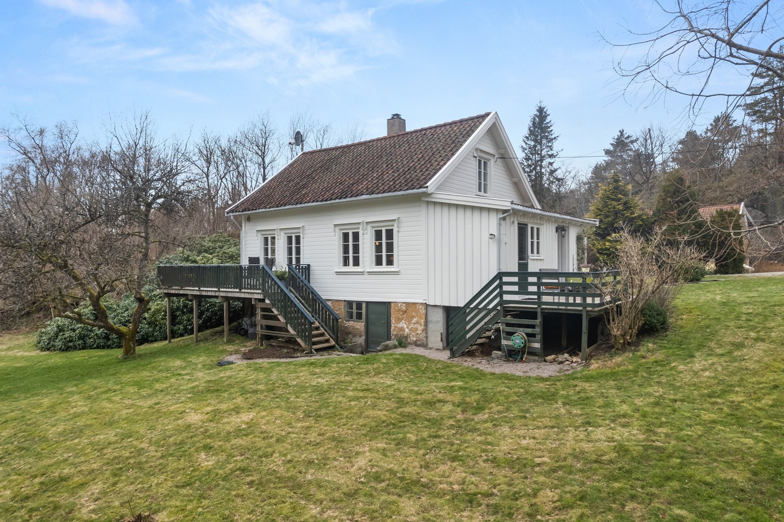 Klassisk enebolig med solrike og flotte uteområder opparbeidet med plen, trær prydbusker og bed Galleribilde