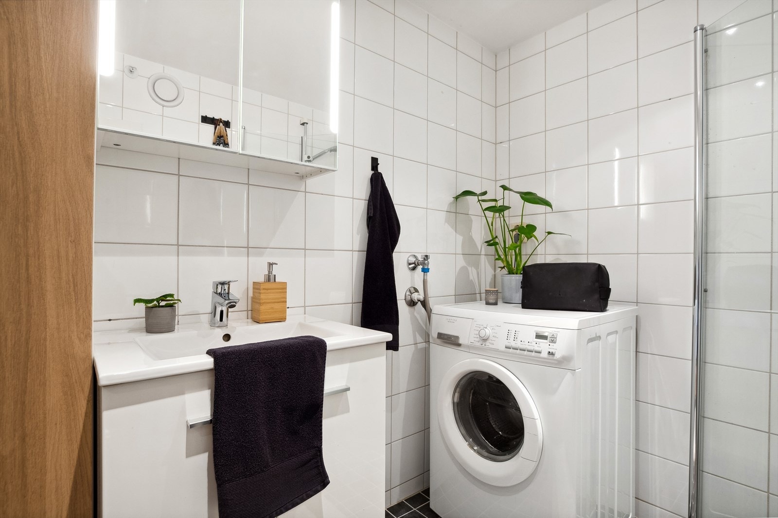 Badet har vegghengt toalett, opplegg for vaskemaskin og et dusjhjørne med innfellbare glassvegger. Galleribilde