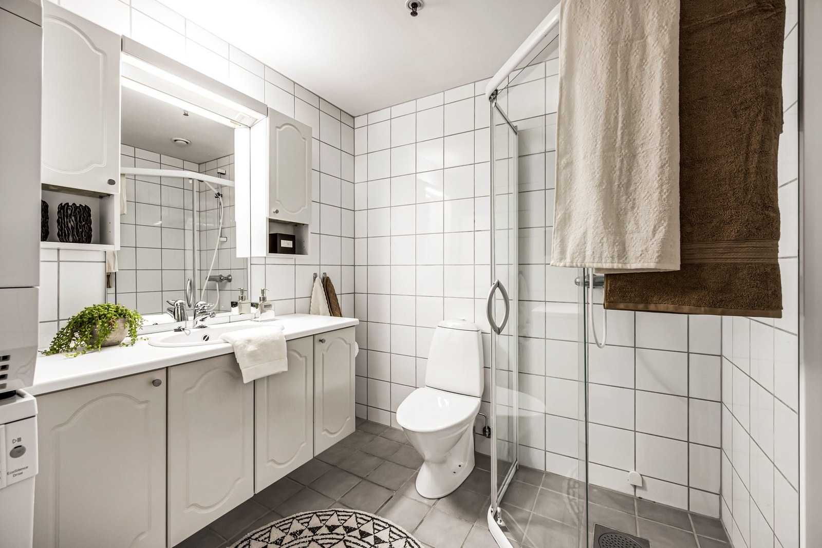 Lyst flislagt baderom med god plass til oppbevaring. Galleribilde