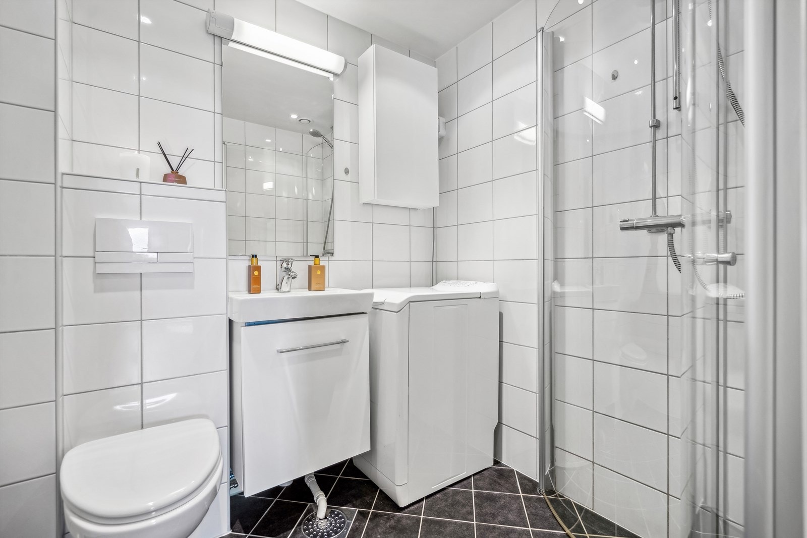 Baderom fra 2013 med tidløse fliser og opplegg for vaskemaskin. Galleribilde