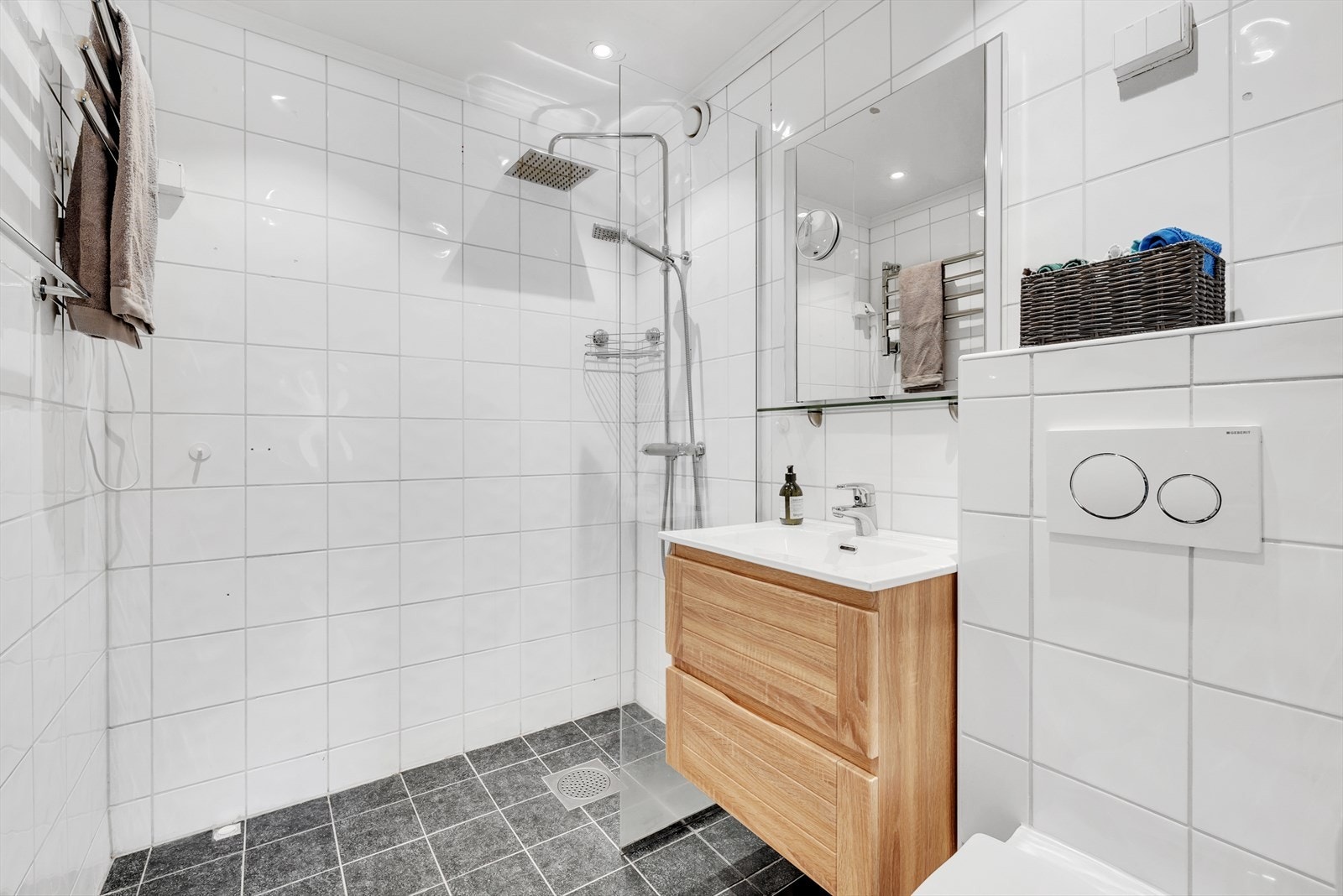 Baderomsinnredningen er bestående av servant
med skuffeseksjon, speil, vegghengt klosett, elektrisk håndkletørker og dusjsone med fast glassvegg. Galleribilde