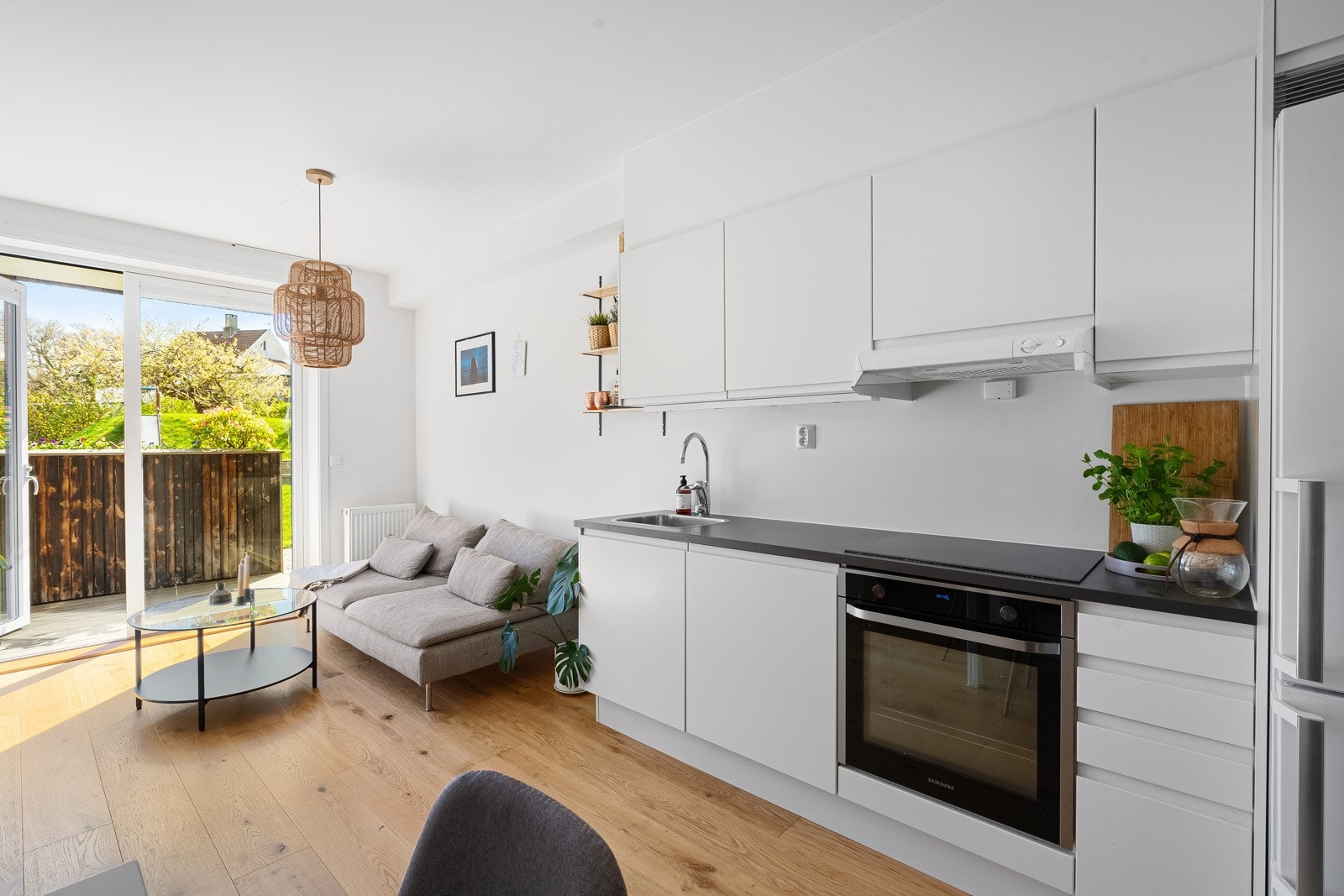 Hvit og stilren kjøkkeninnredning med integrert komfyr, koketopp og oppvaskmaskin Galleribilde