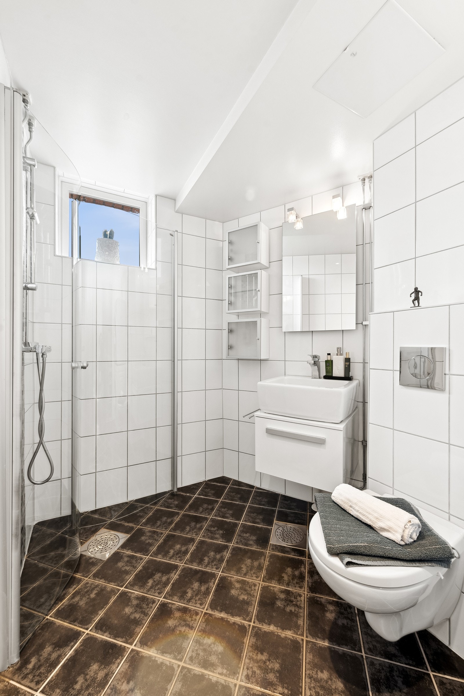 Pent flislagt bad rehabilitert av borettslaget i 2012. Varmekabler i gulv, innvsingbare dusjdører i glass, og benkeskap med utenpåliggende vaskeseservant. Galleribilde