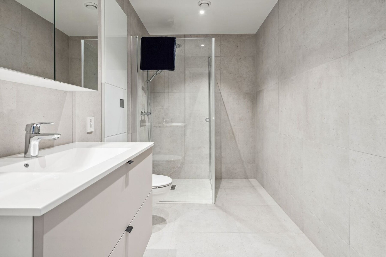 Bad med vegghengt toalett, dusj, speilskap og servant. Galleribilde