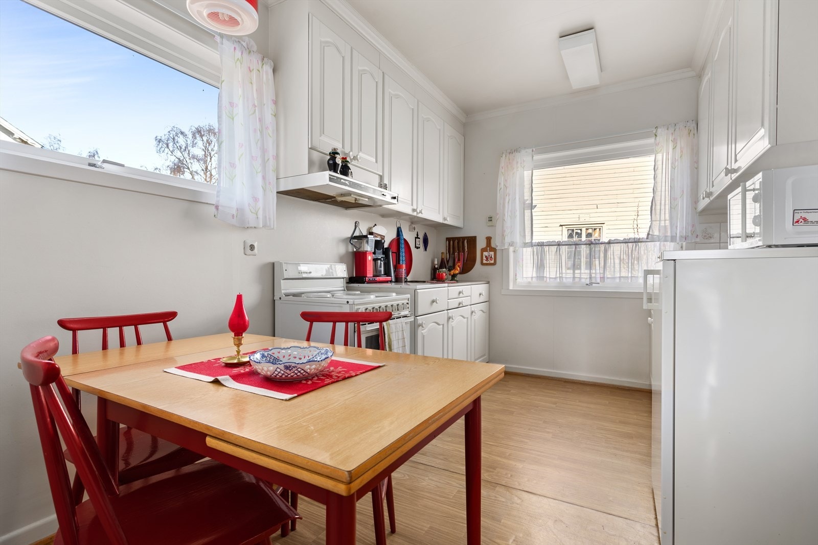 Koseleg kjøkken med kvit kjøkkeninnreiing med profilerte frontar. Galleribilde