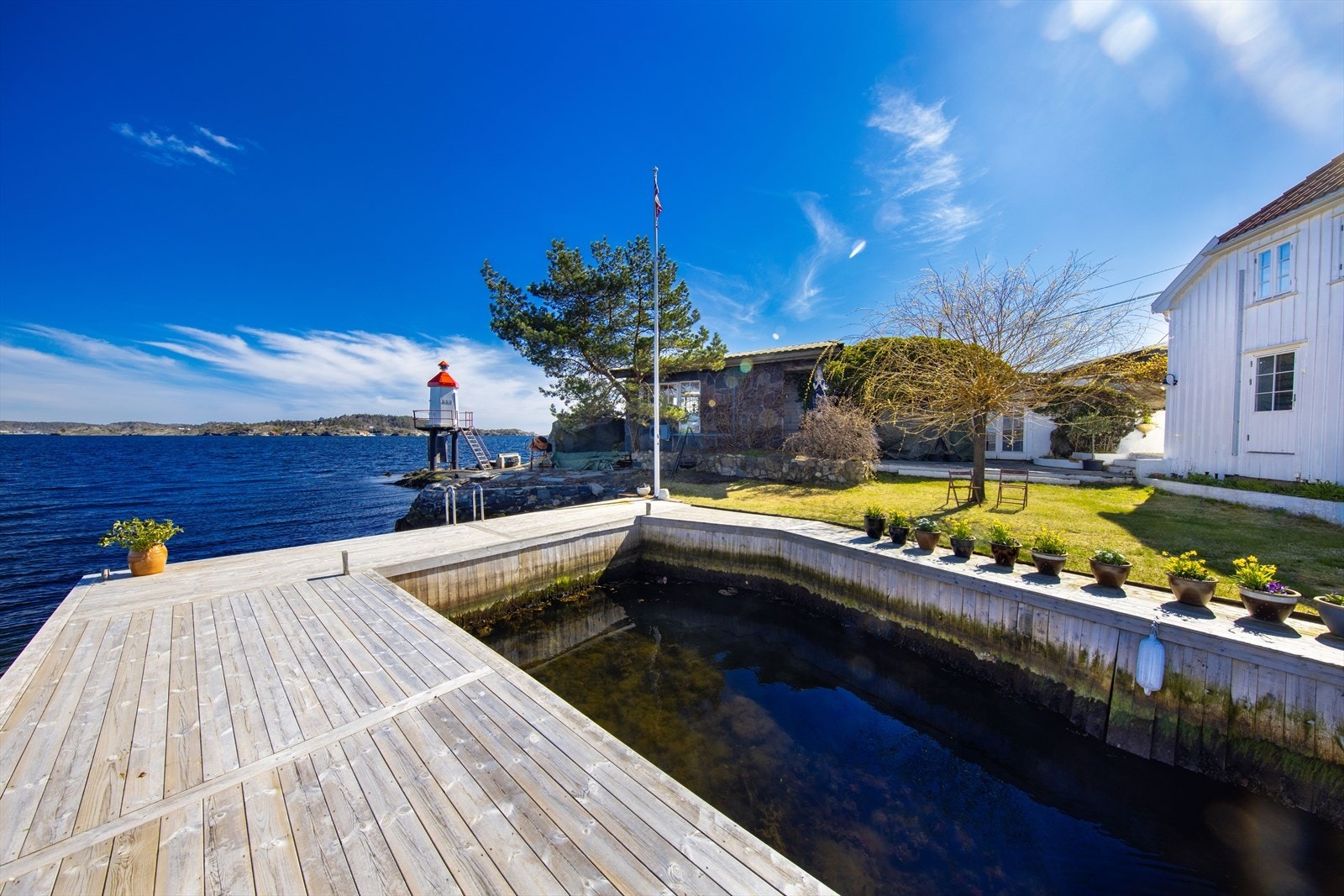 Strandeiendom spektakulært beliggende på spissen av Øya med enebolig, verkstedsbygning og solid bryggeanlegg! Galleribilde